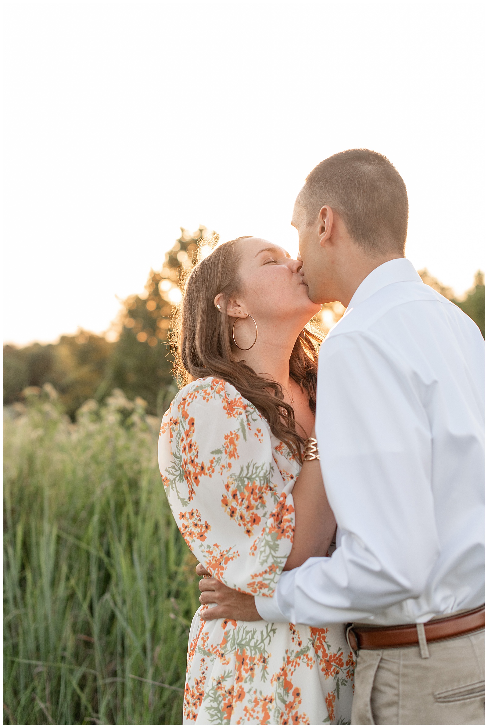 engaged couple kissing at sunset by field of wildflowers at overlook park