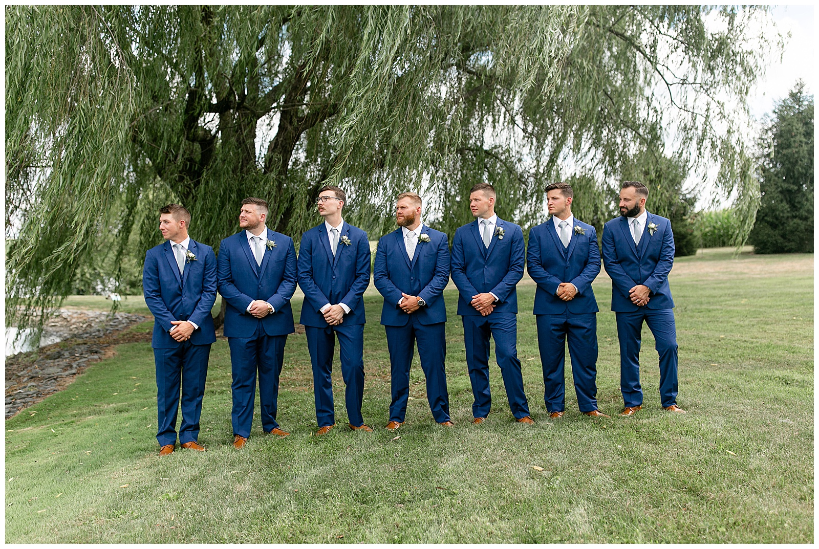 groom and groomsmen all standing in a row with hands folded and all looking to the right at lakefield weddings