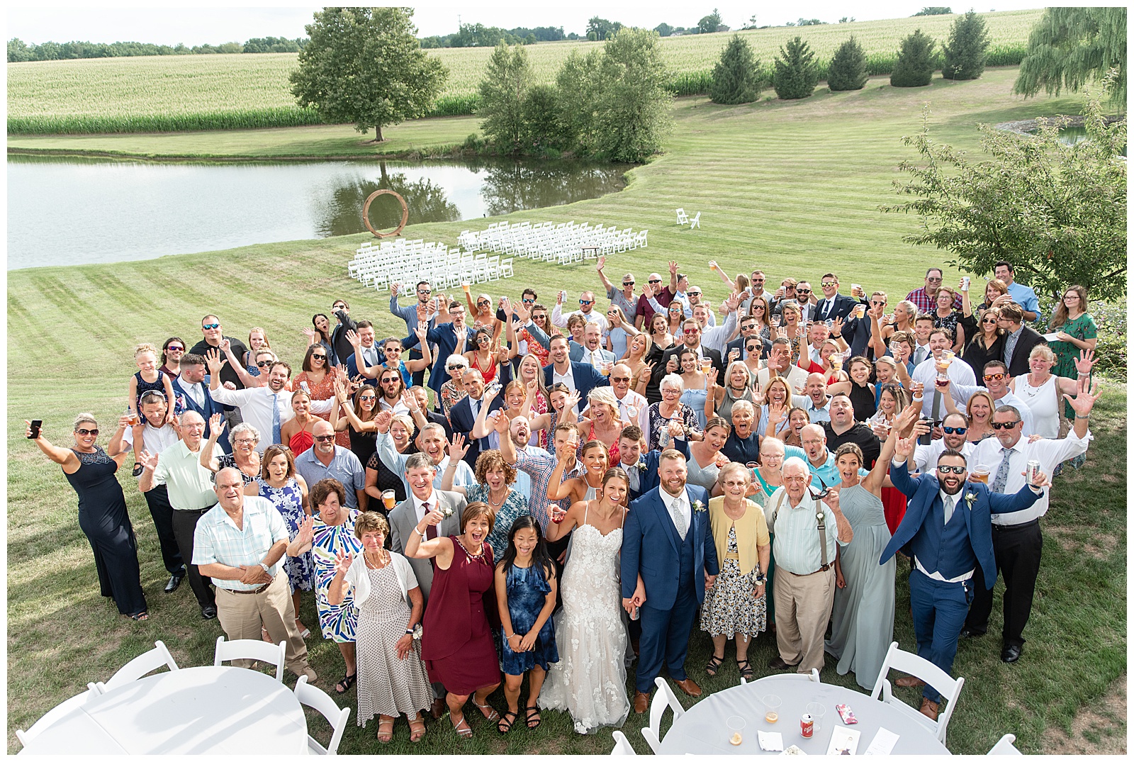 aerial photo of bride and groom with all of their guests cheering outside on sunny summer day by pond at lakefield weddings in manheim pennsylvania