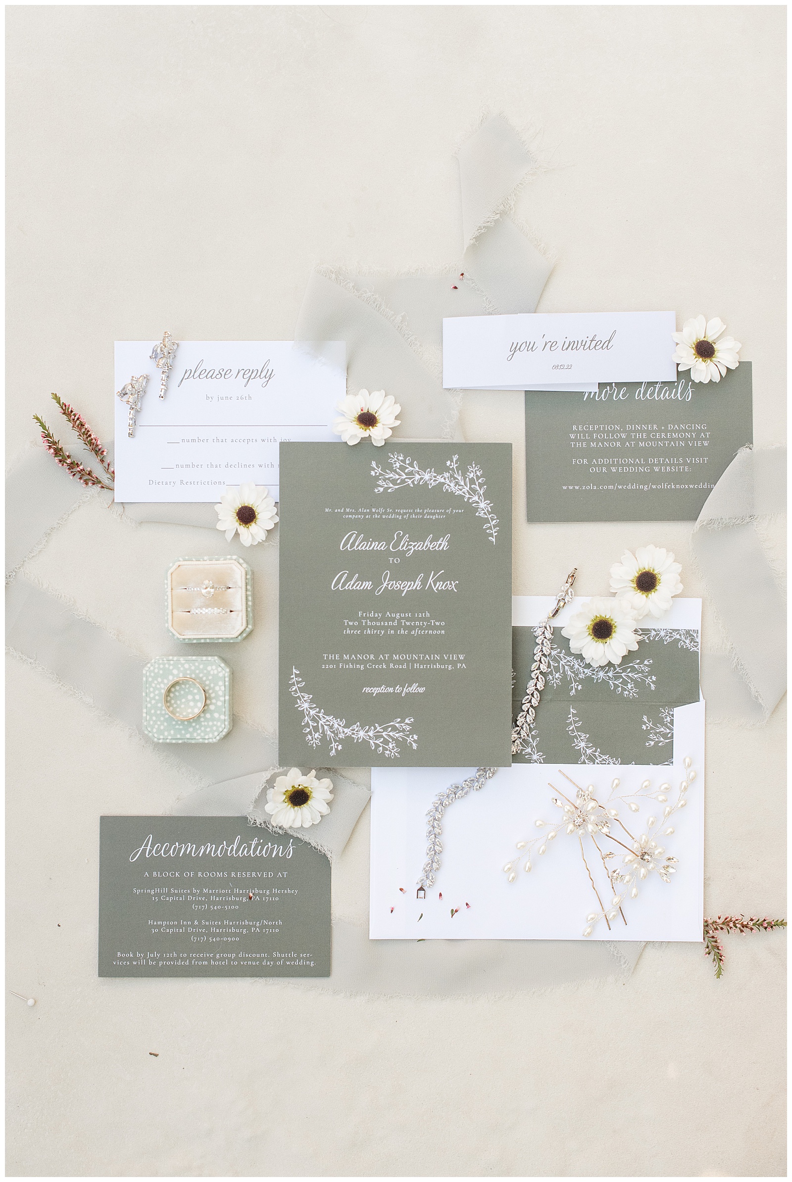 wedding invitation displayed with jewelry and rings and white daisies at the manor at mountain view