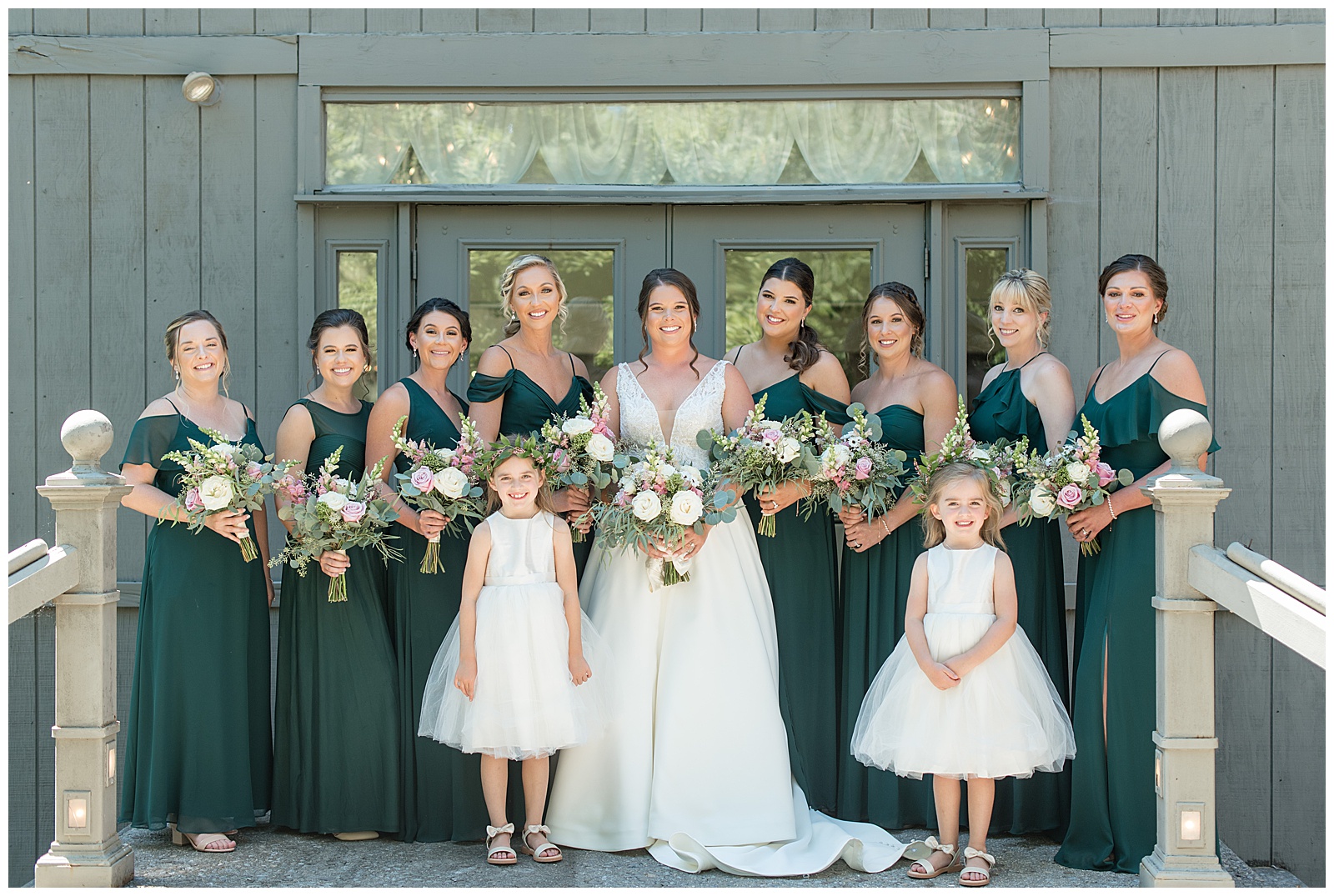 bride surrounded by her eight bridesmaids and two flower girls by gray doors all holding bouquets in harrisburg pennsylvania