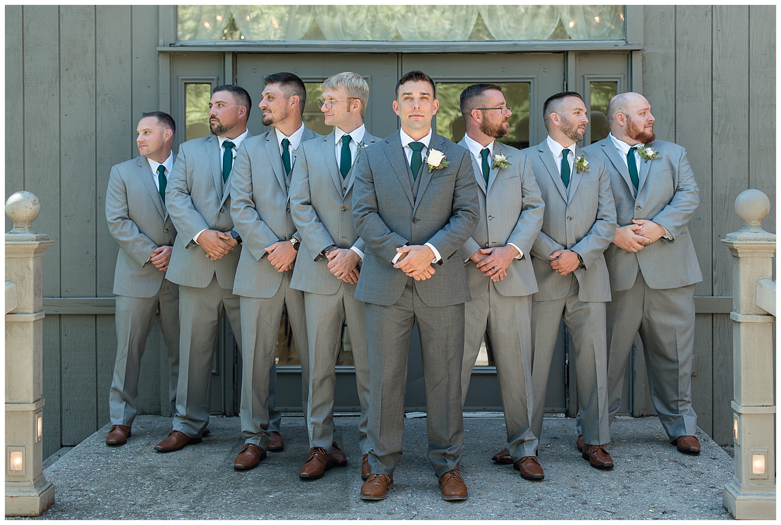 groom with his seven groomsmen all in gray suits with dark green ties look in opposite directions in harrisburg pennsylvania
