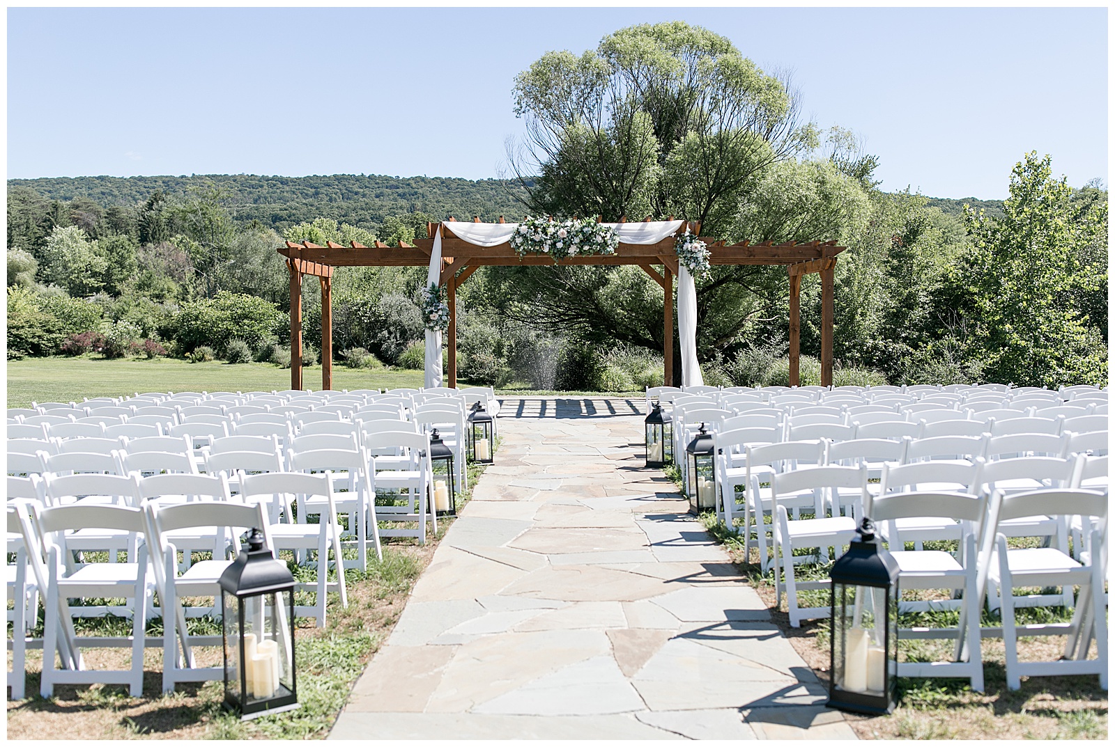 outdoor wedding ceremony set up with rows of white chairs and beautiful wooden display with white linen draped by mountain views in harrisburg pennsylvania