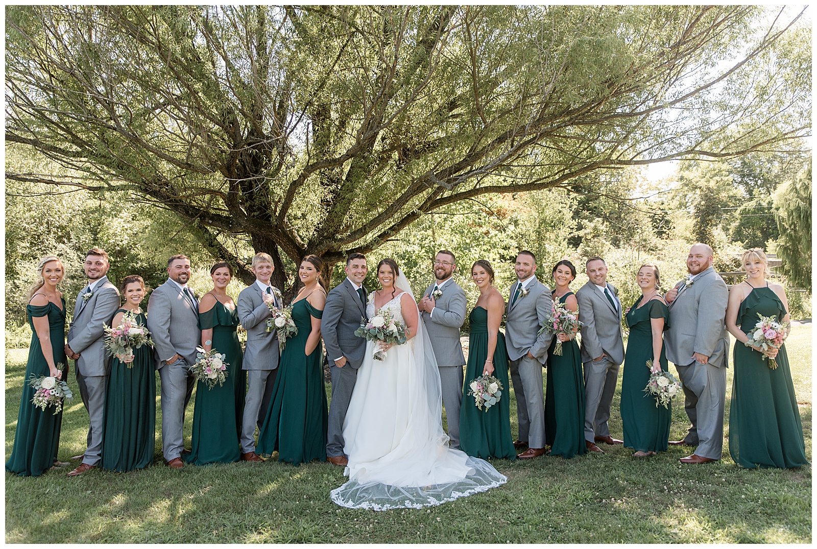 couple surrounded by their bridal party under tree at the manor at mountain view in harrisburg pennsylvania