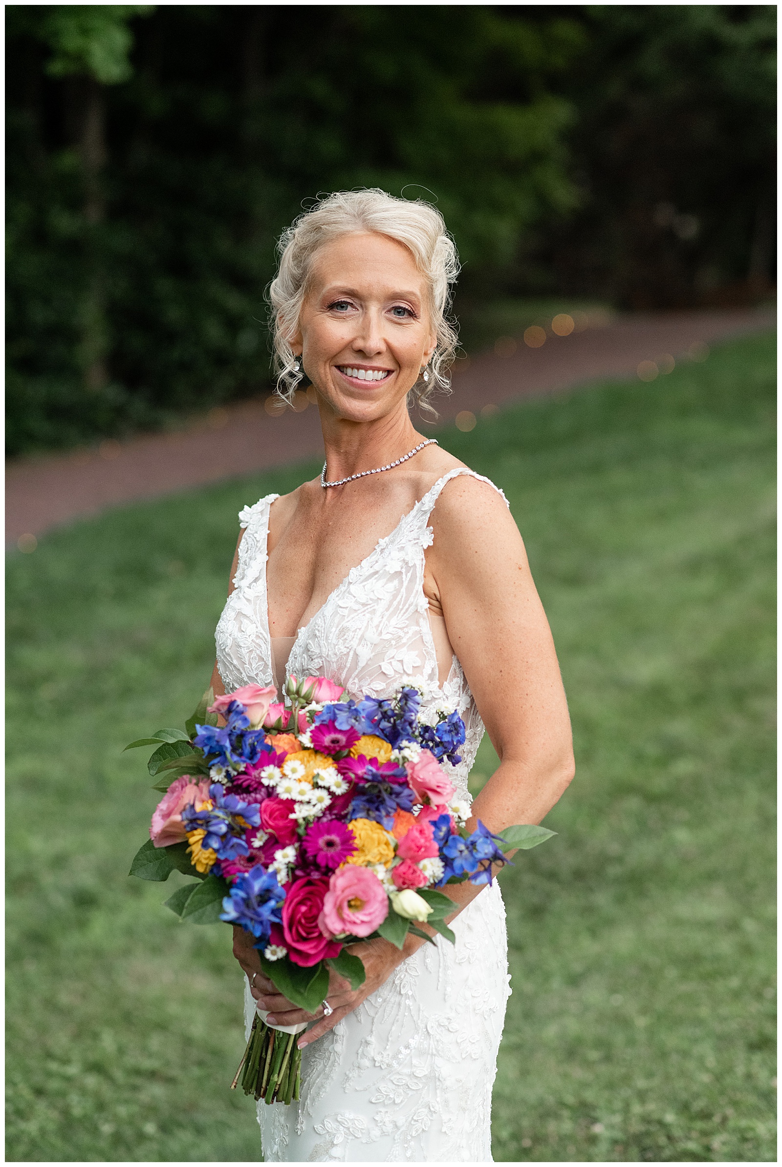 bride in white sleeveless gown with v-neck holding vibrant bouquet of flowers at the inn at leola village in lancaster county