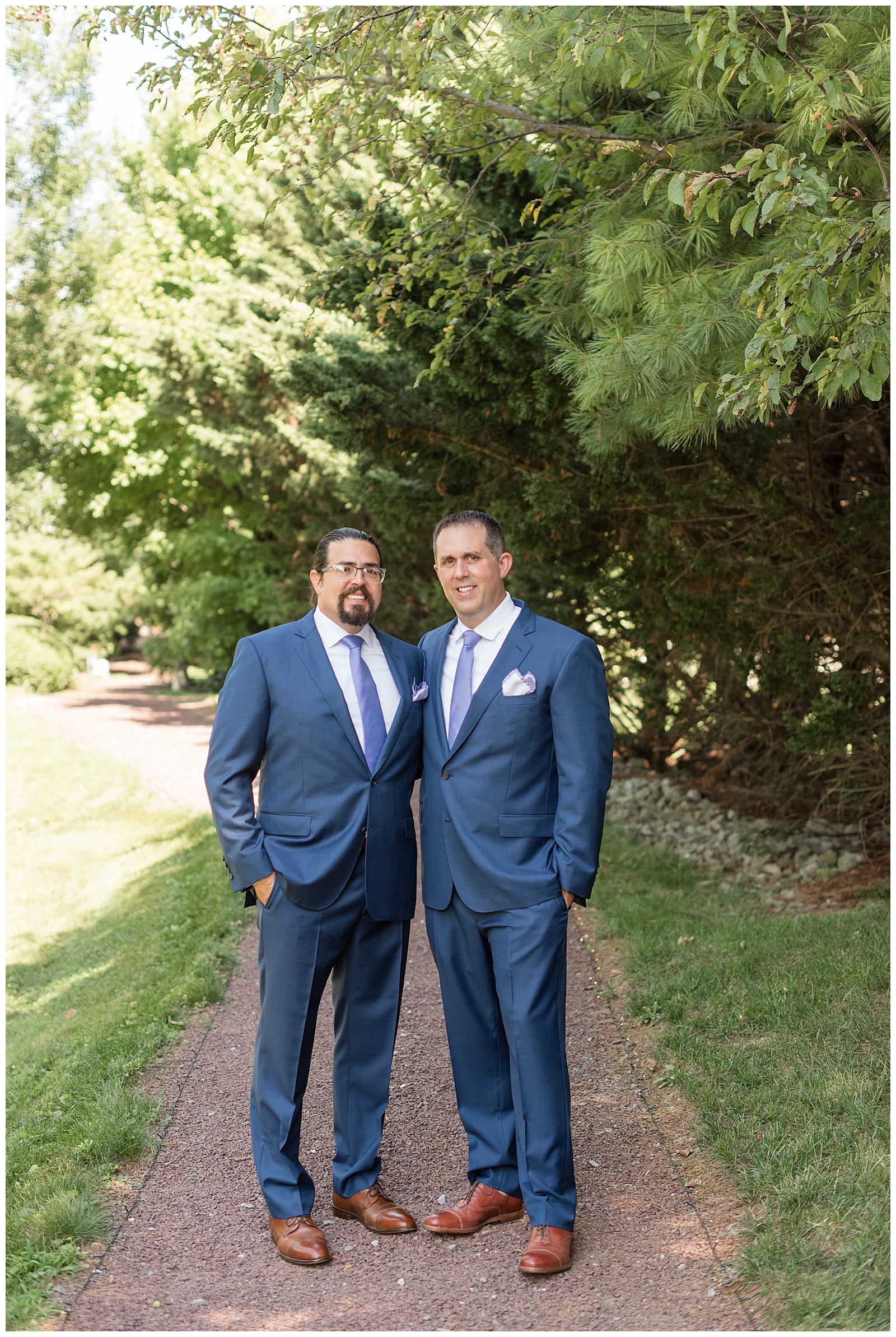 groom with his one groomsman standing on pathway with their hands in their pockets at the inn at leola village