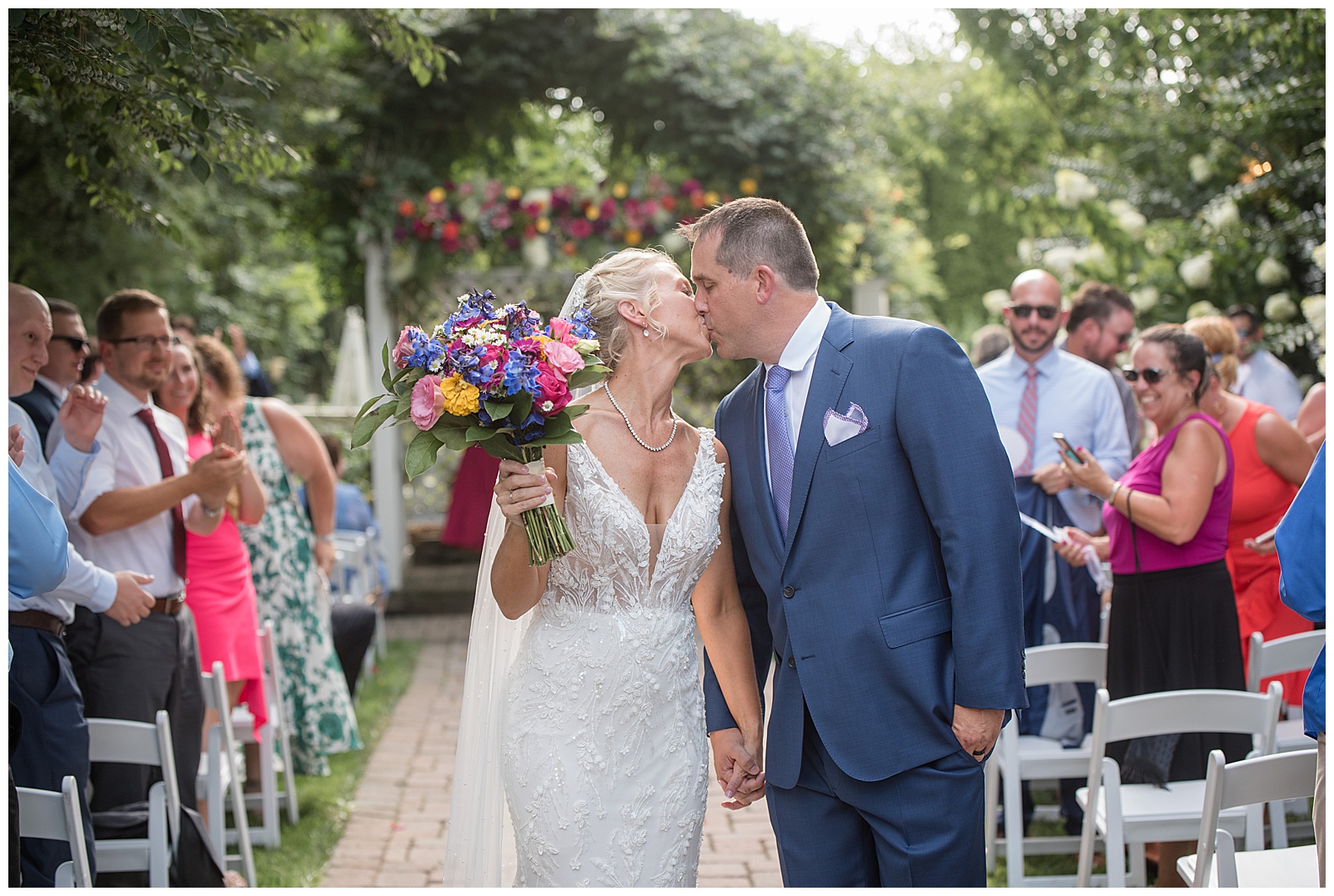 bride and groom kiss at the end of aisle as they leave outdoor wedding ceremony at the inn at leola village