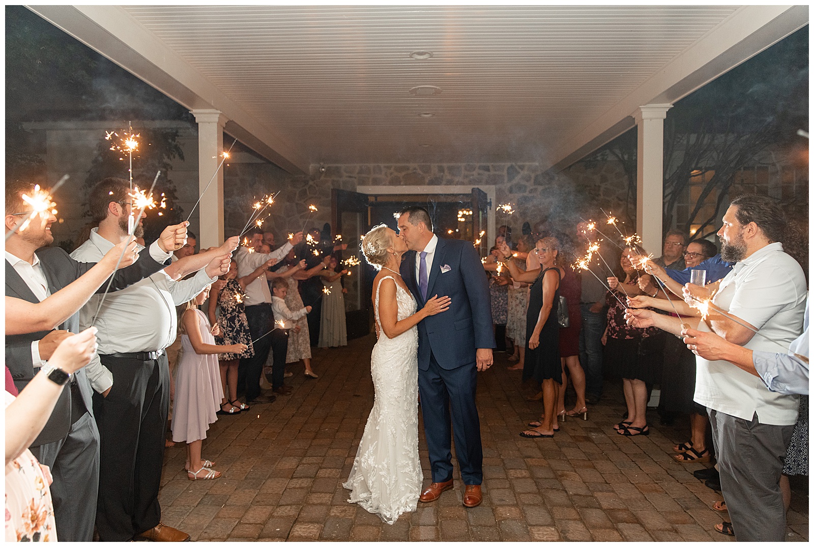 couple kissing in aisle of guests holding sparklers as they leave their wedding reception at the inn at leola village