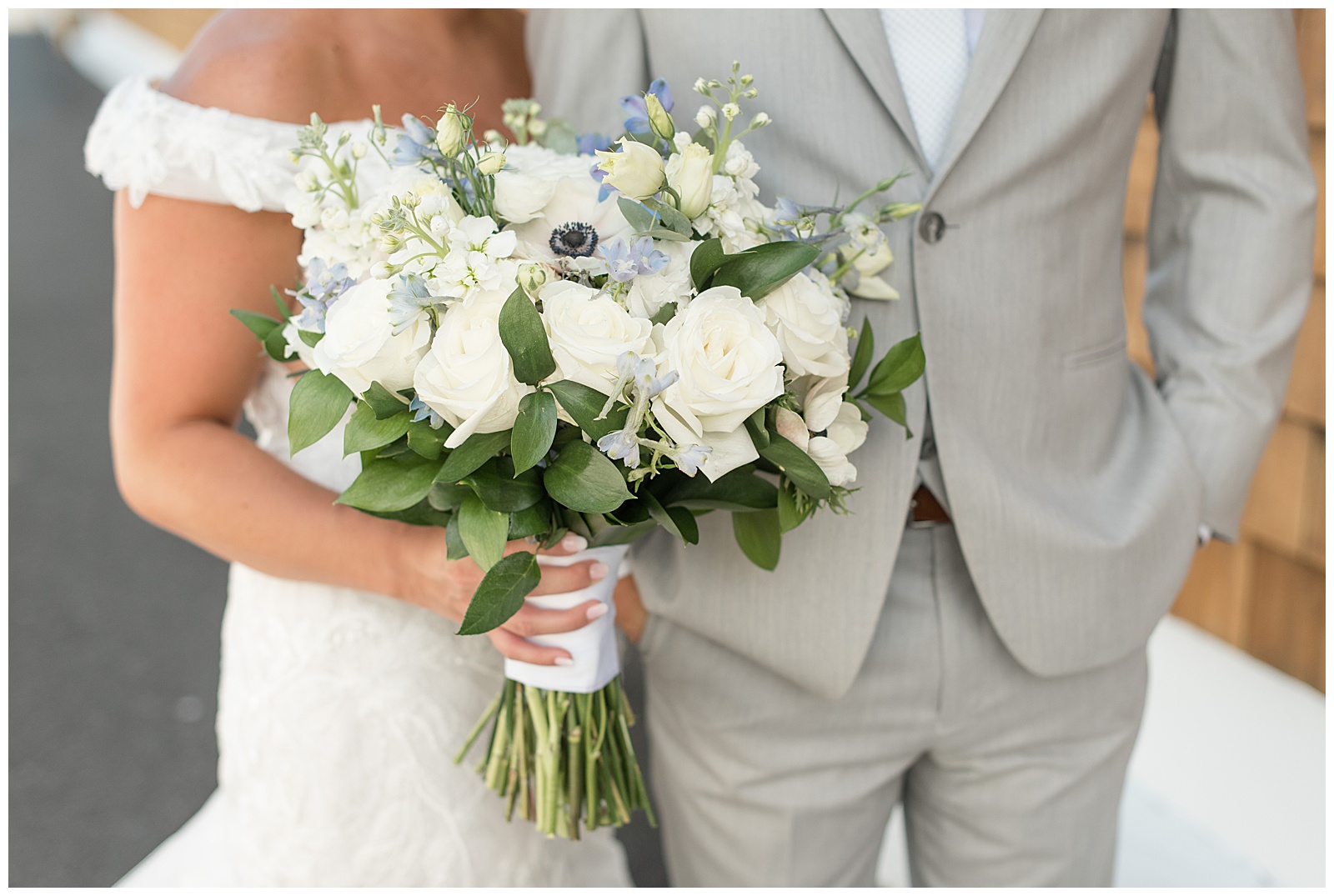 close up photo of bride's bouquet filled with white roses and tiny blue flowers in new york