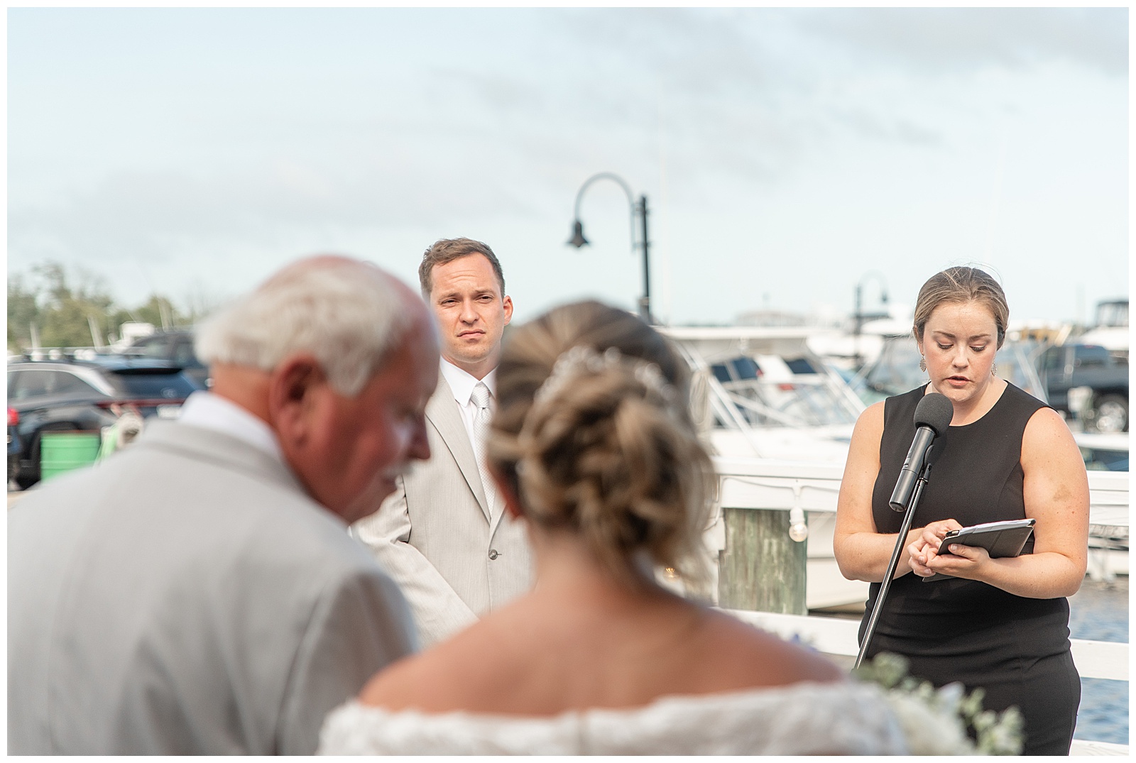 groom looking at his bride and she's being walking down the aisle by her father at waterfront ceremony in bay shore new york
