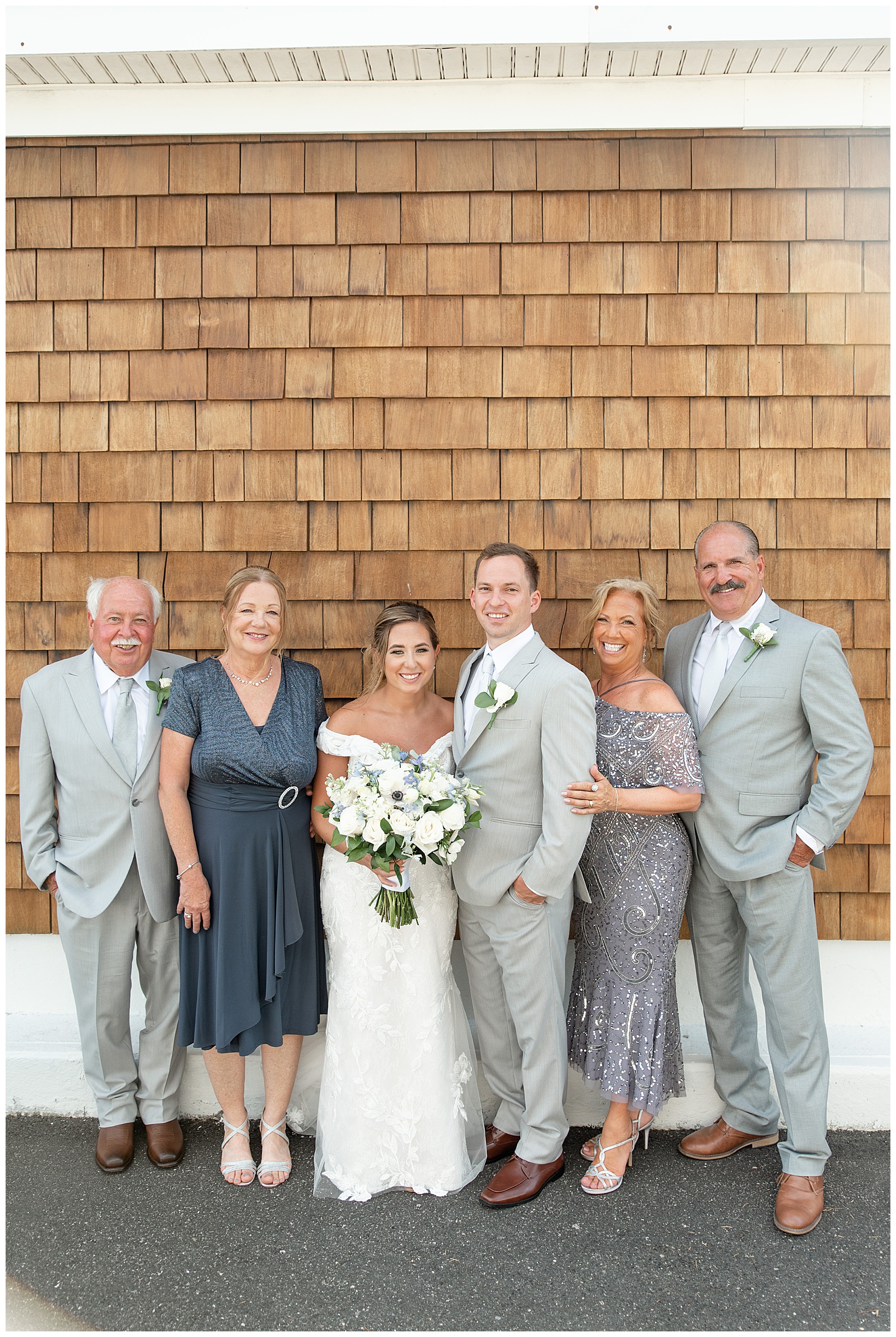 bride and groom with both sets of their parents by tan building at captain bill's in bay shore, new york