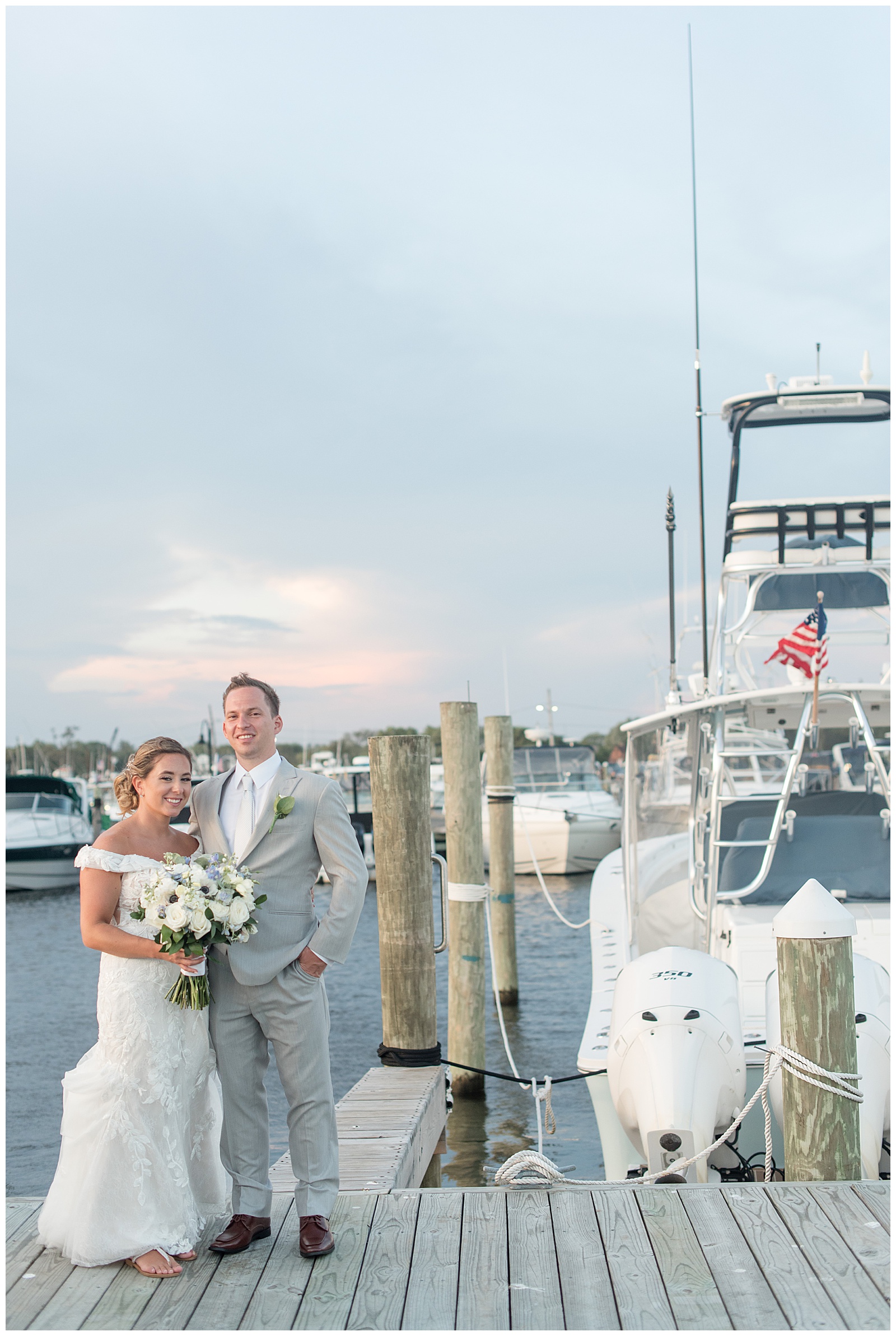 couple standing on dock by large boat at sunset on summer wedding day in bay shore new york