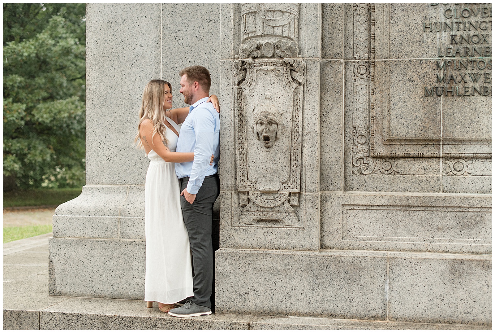 engaged couple standing close together smiling as woman wraps her arms around her man beside the national memorial arch in pennsylvania