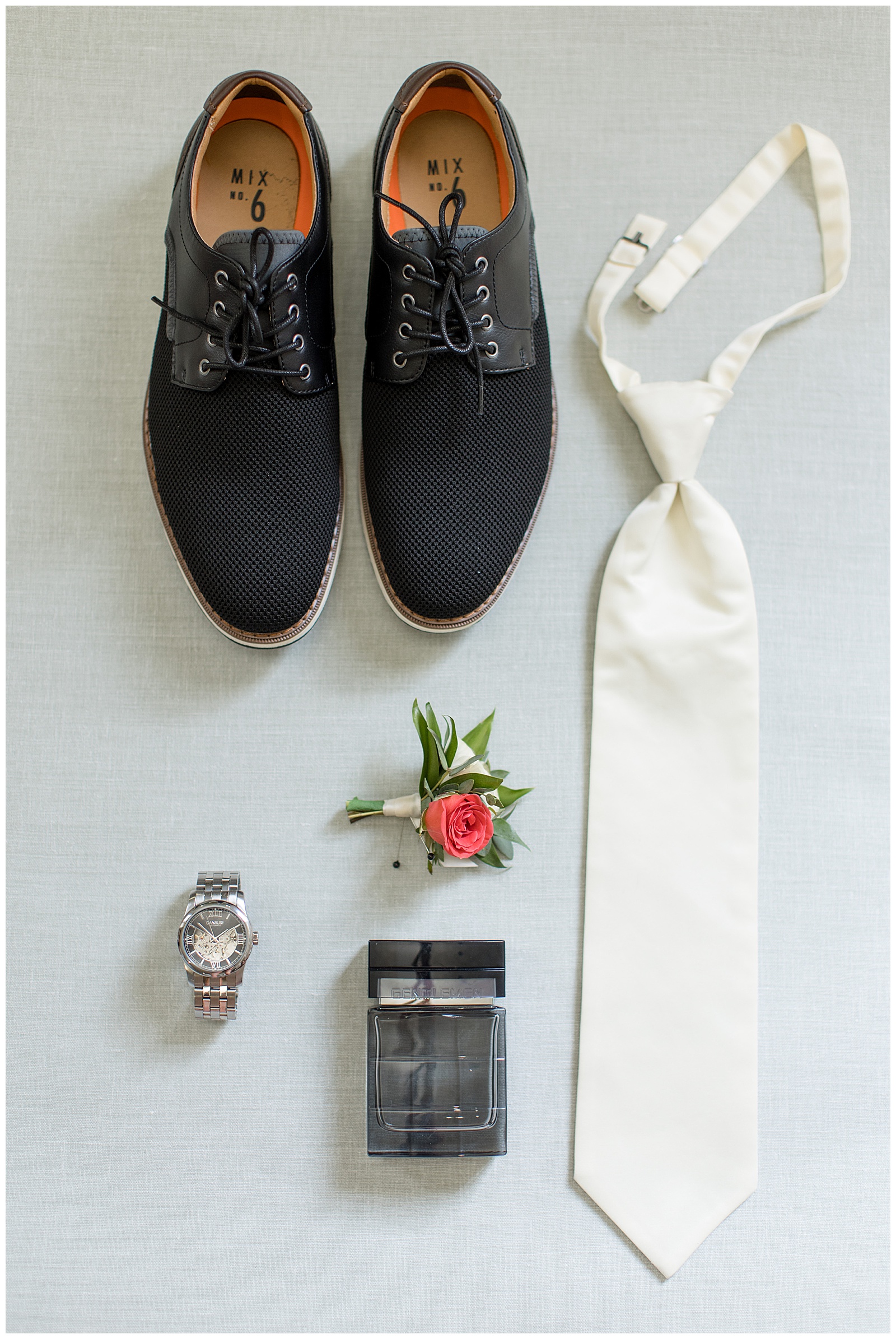 groom's black shoes displayed with his white tie, boutonniere, wrist watch and bottle of cologne in lancaster county