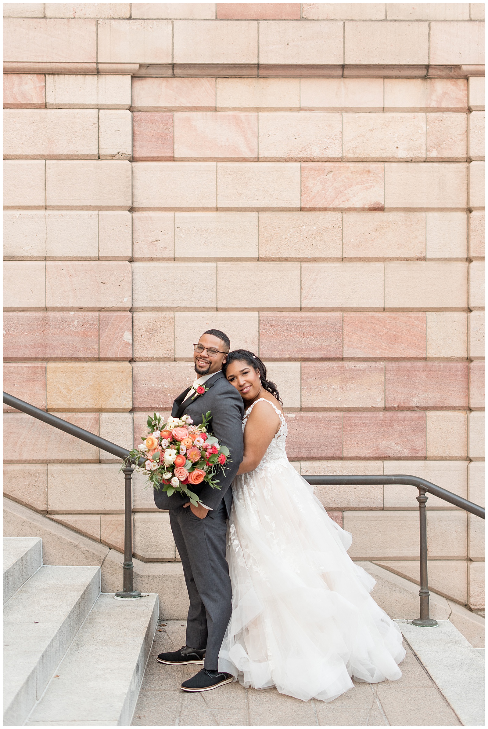 bride hugging her groom from behind and resting her right cheek on his back as they stand on the county courthouse steps in lancaster county pennsylvania