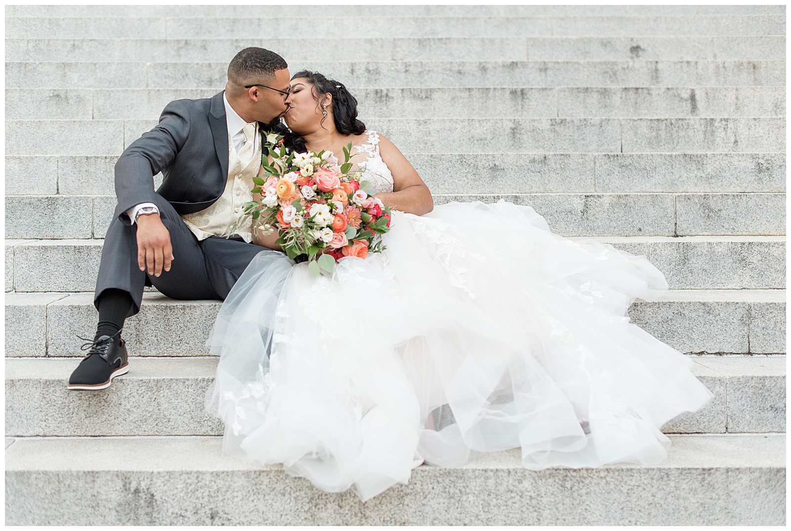 bride and groom sitting on concrete courthouse steps and kissing on summer day in lancaster county, pennsylvania