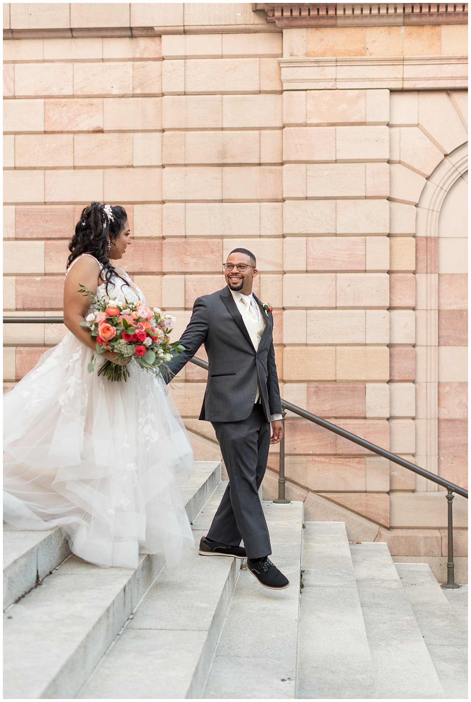 groom leading his bride down the courthouse steps outside on a sunny evening in lancaster's penn square