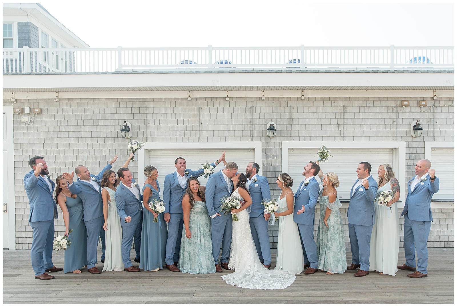 bride and groom kissing as their bridal party surrounds them cheering with arms raised in new jersey
