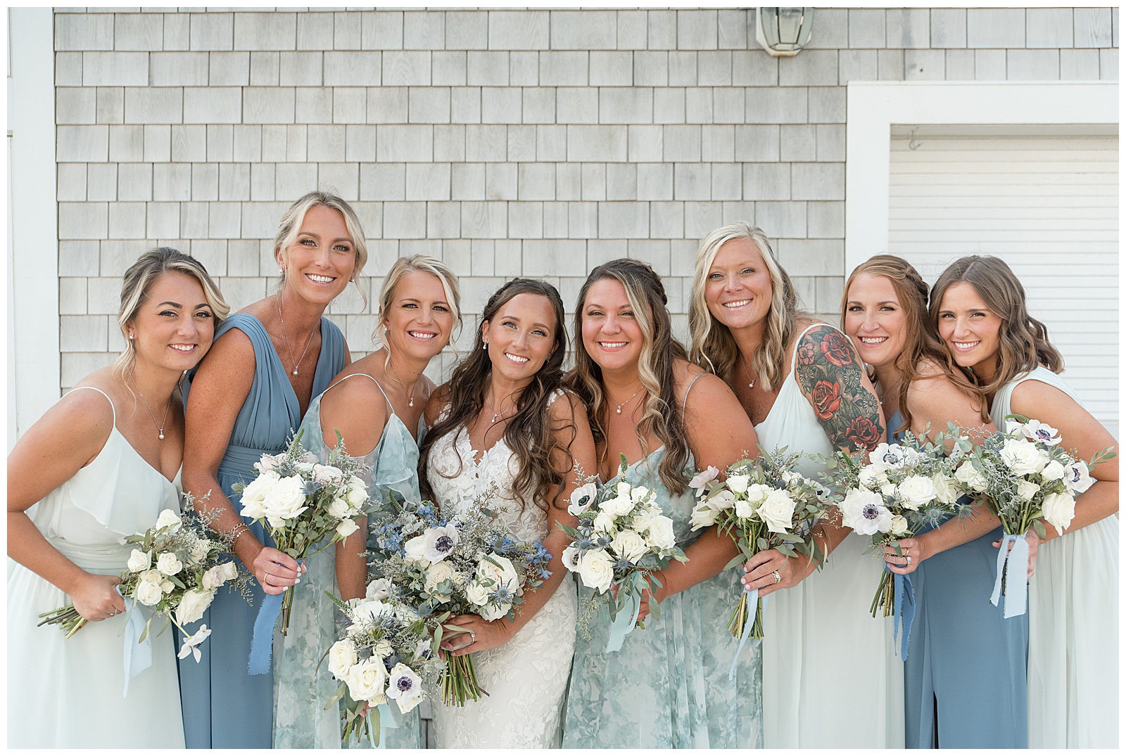 bride with her bridesmaids leaning in towards her smiling holding bouquets in Avon by the Sea