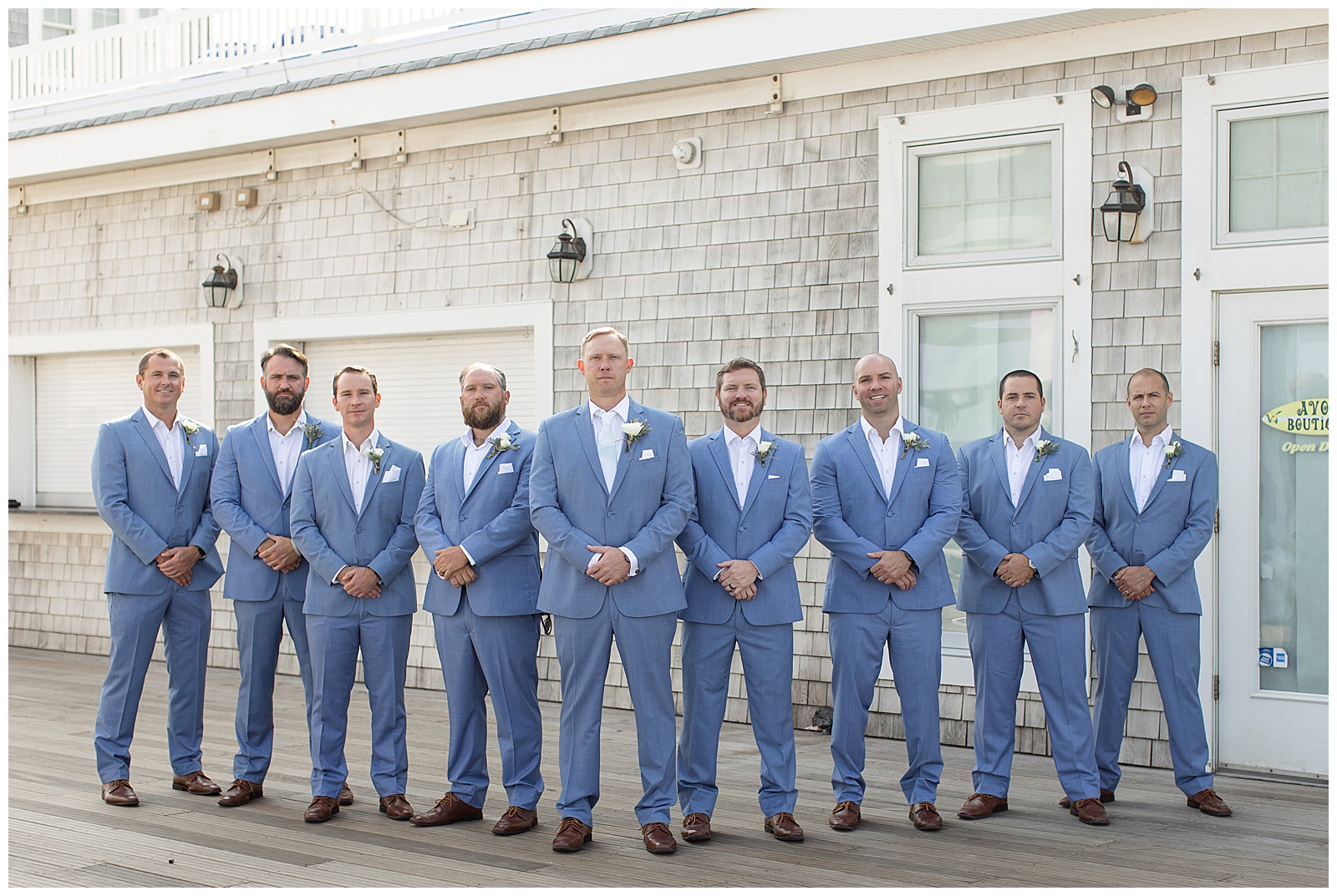 groom surrounded by his six groomsmen all in dark blue suits with hands folded in front in new jersey