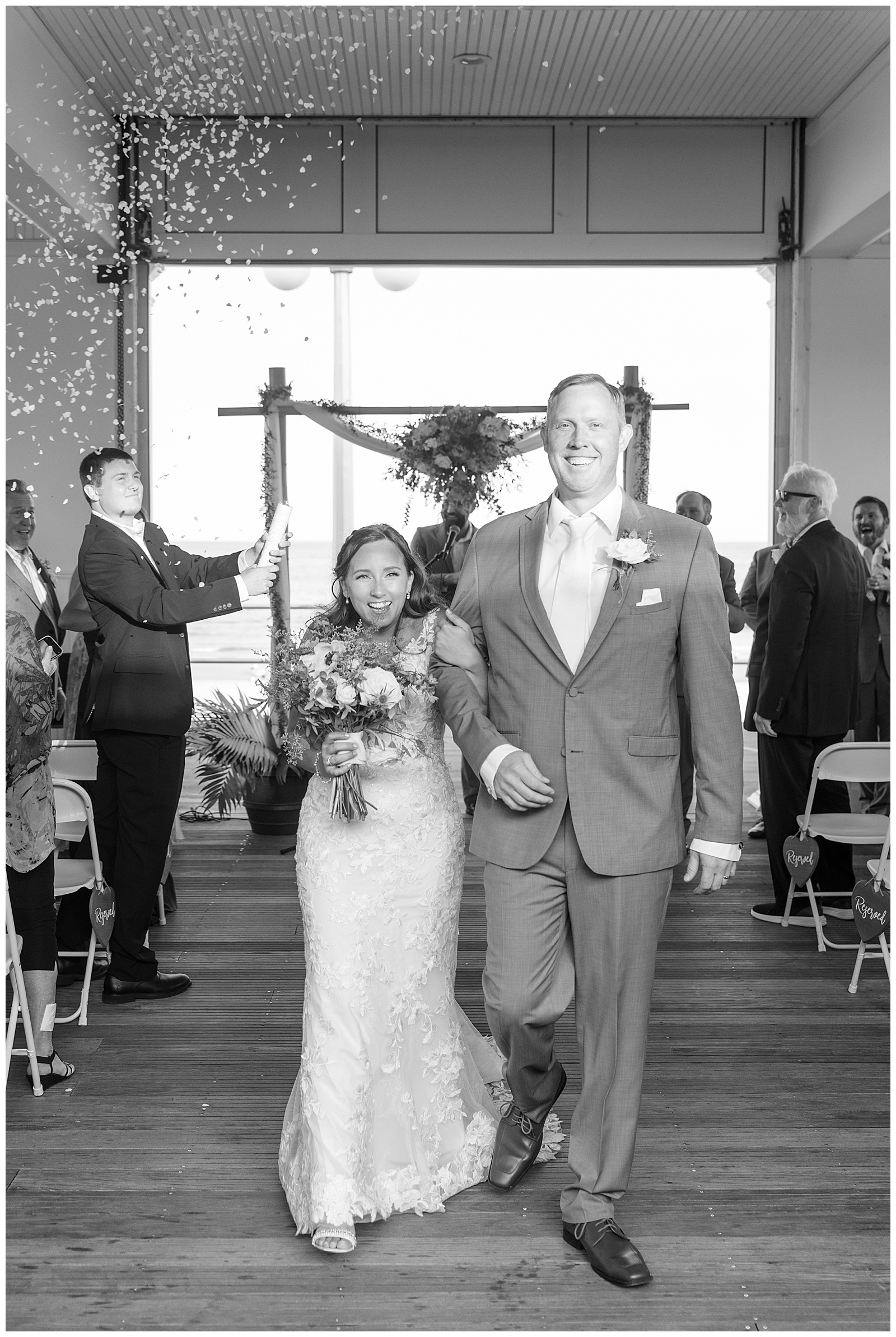black and white photo of bride and groom smiling and holding onto each other as they leave their wedding ceremony in new jersey