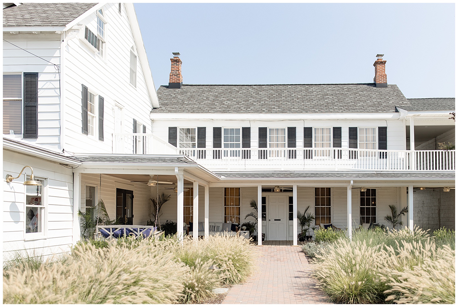 beautiful white beach house with black shutters and wrap-around front porch on a sunny day in maryland