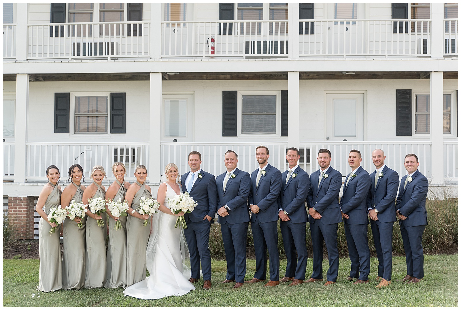coupl with their bridal party in front of large white house with two-story front porch on tilghman island