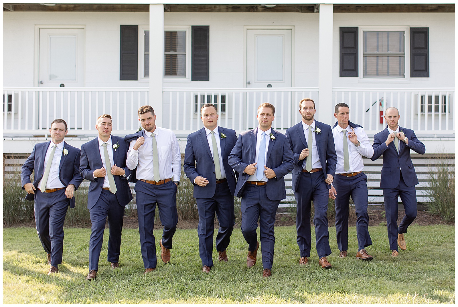 groom and his groomsmen all casually walking towards camera with some holding suit coat over their shoulder on tilghman island