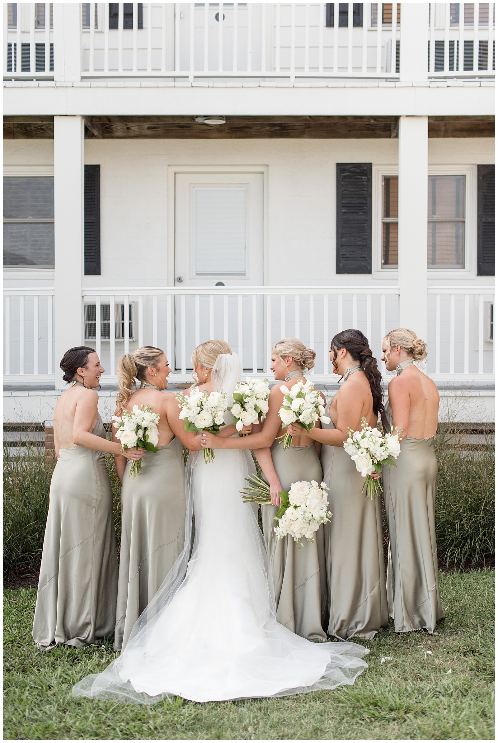 bride and her bridesmaids with backs toward camera and arms wrapped around one another holding bouquets at wylder hotel