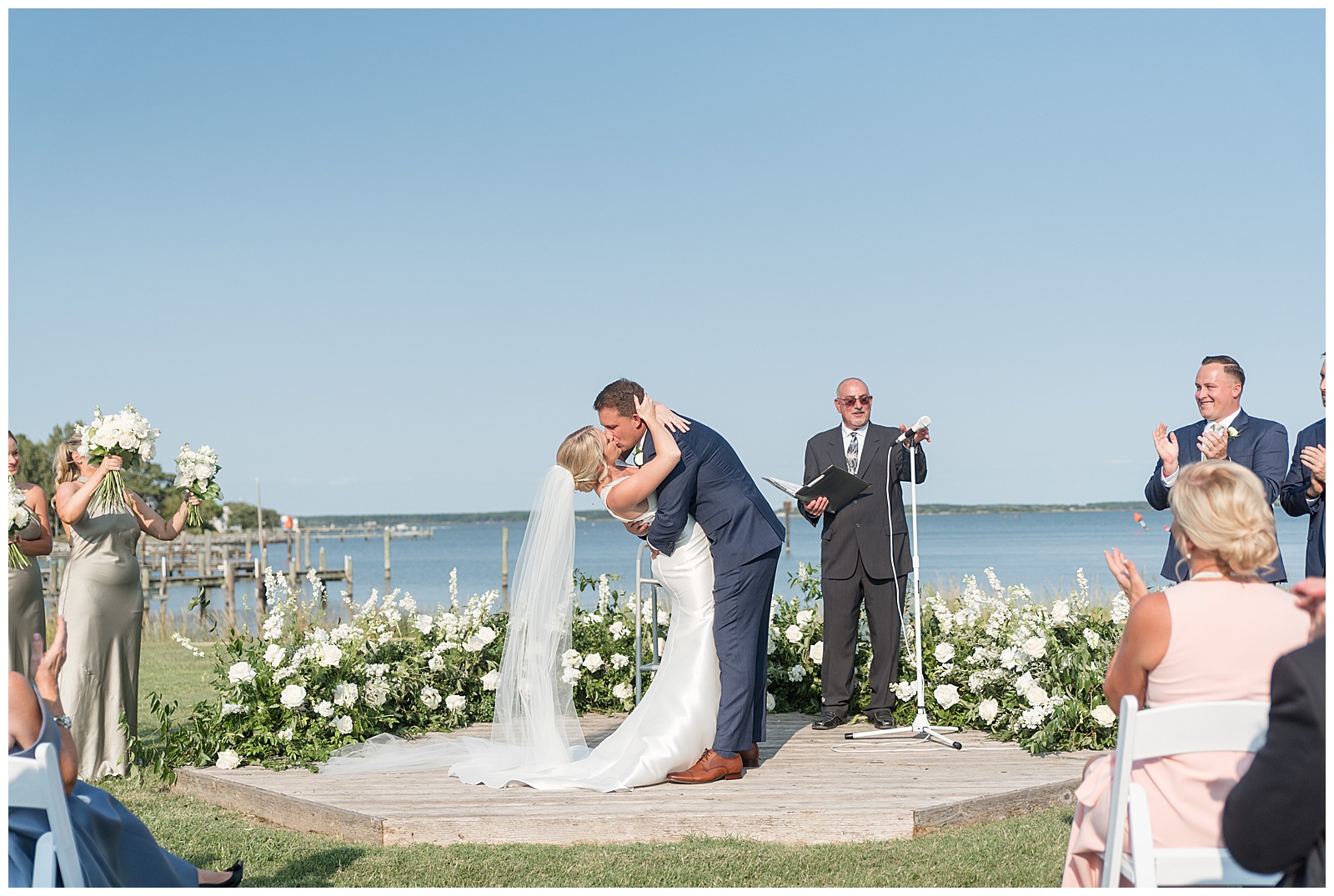 groom dipping back his bride as they share their first kiss during outdoor wedding ceremony on tilghman island