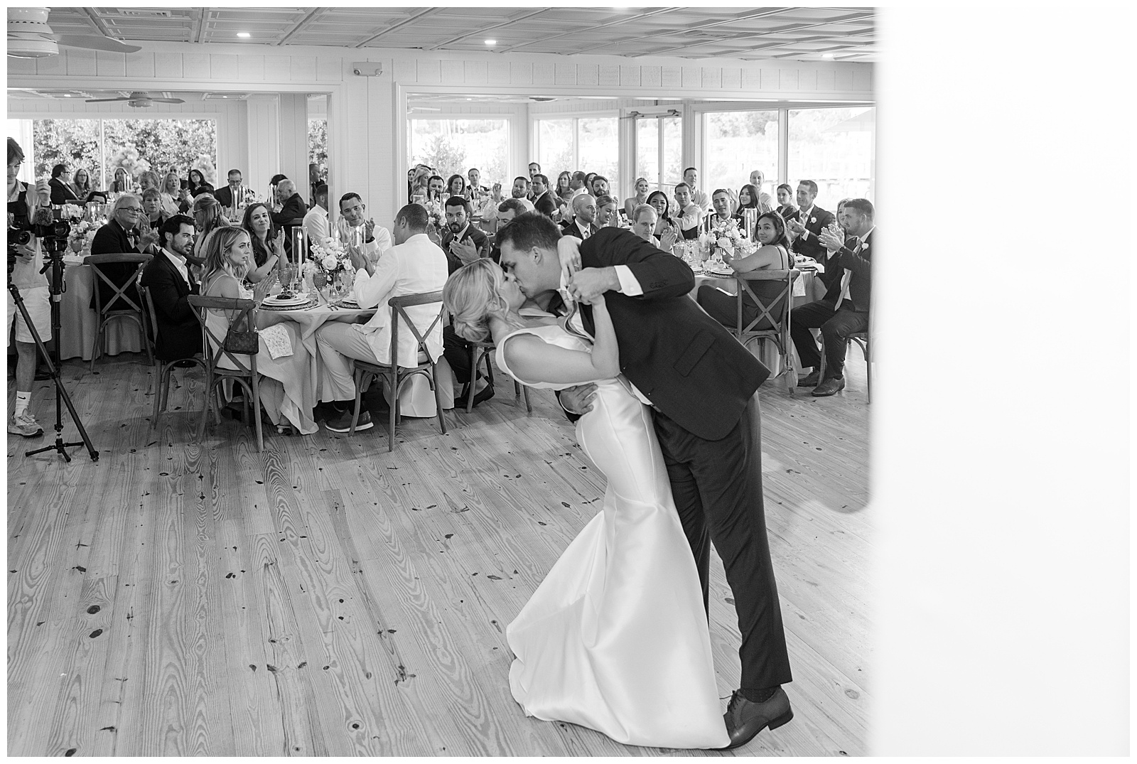 black and white photo of groom dipping back and kissing his bride during first dance of indoor reception at wylder hotel