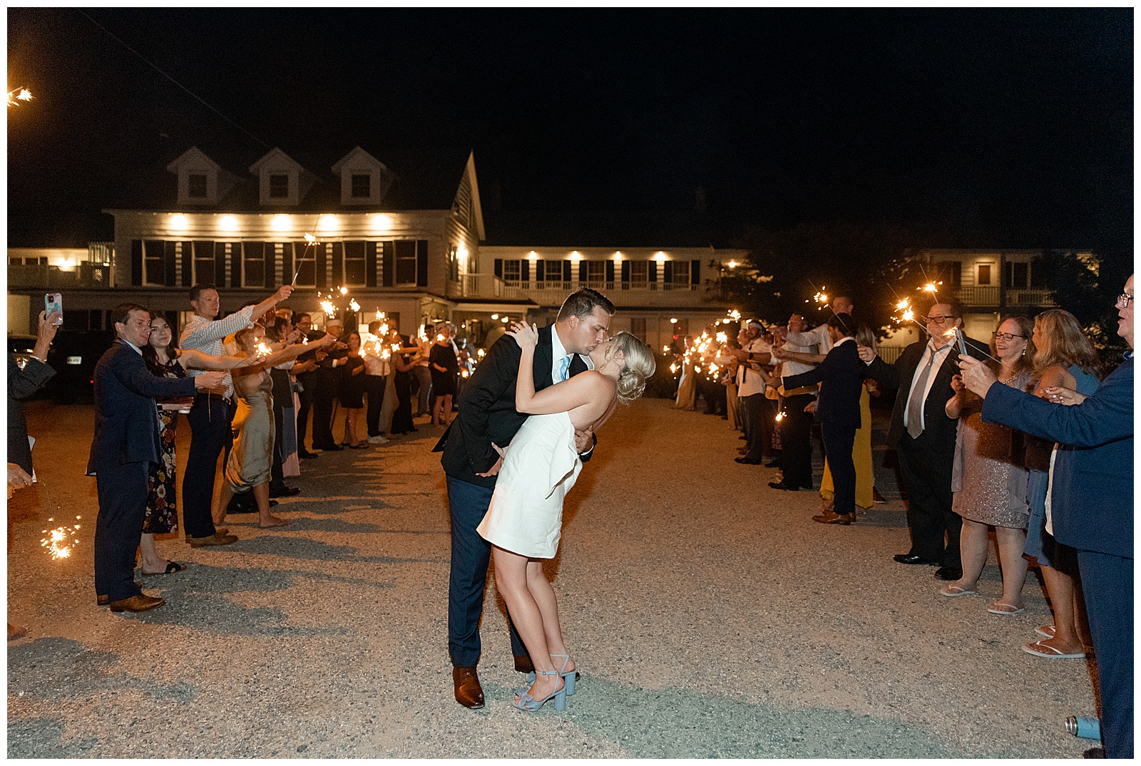 bride and groom sharing a last kiss between two rows of their guests with sparklers at nighttime on tilghman island