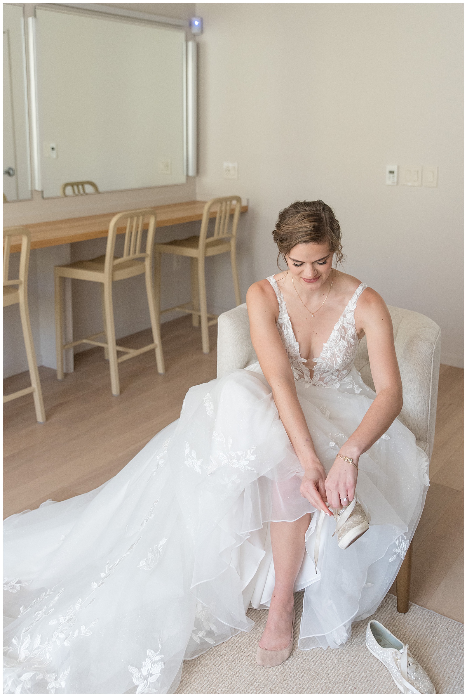 beautiful bride sitting in bridal suite in her gown and lacing up her white keds on wedding at elizabeth furnace