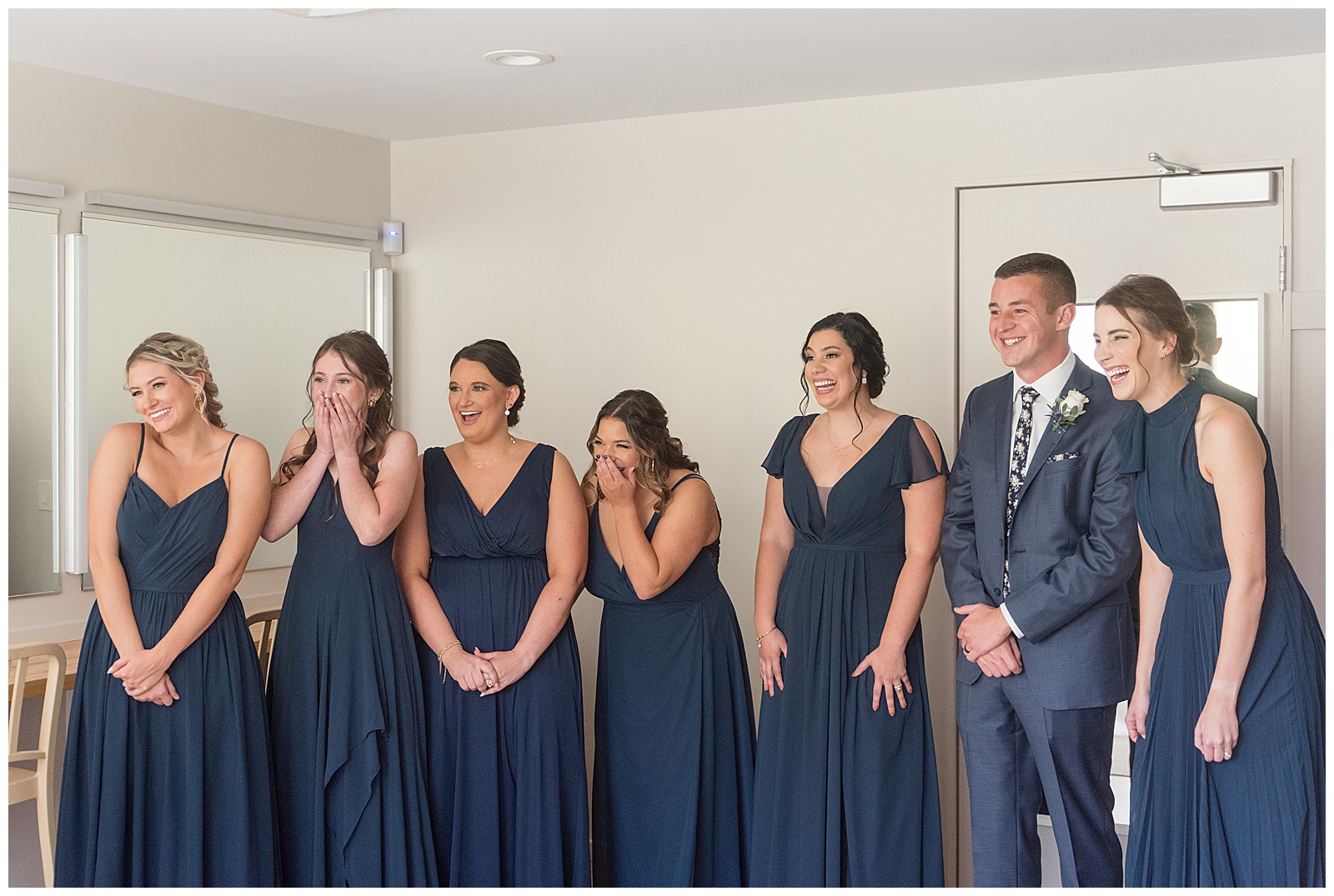 six bridesmaids and one bridesman all wearing navy blue reacting to seeing the bride in suite at elizabeth furnace