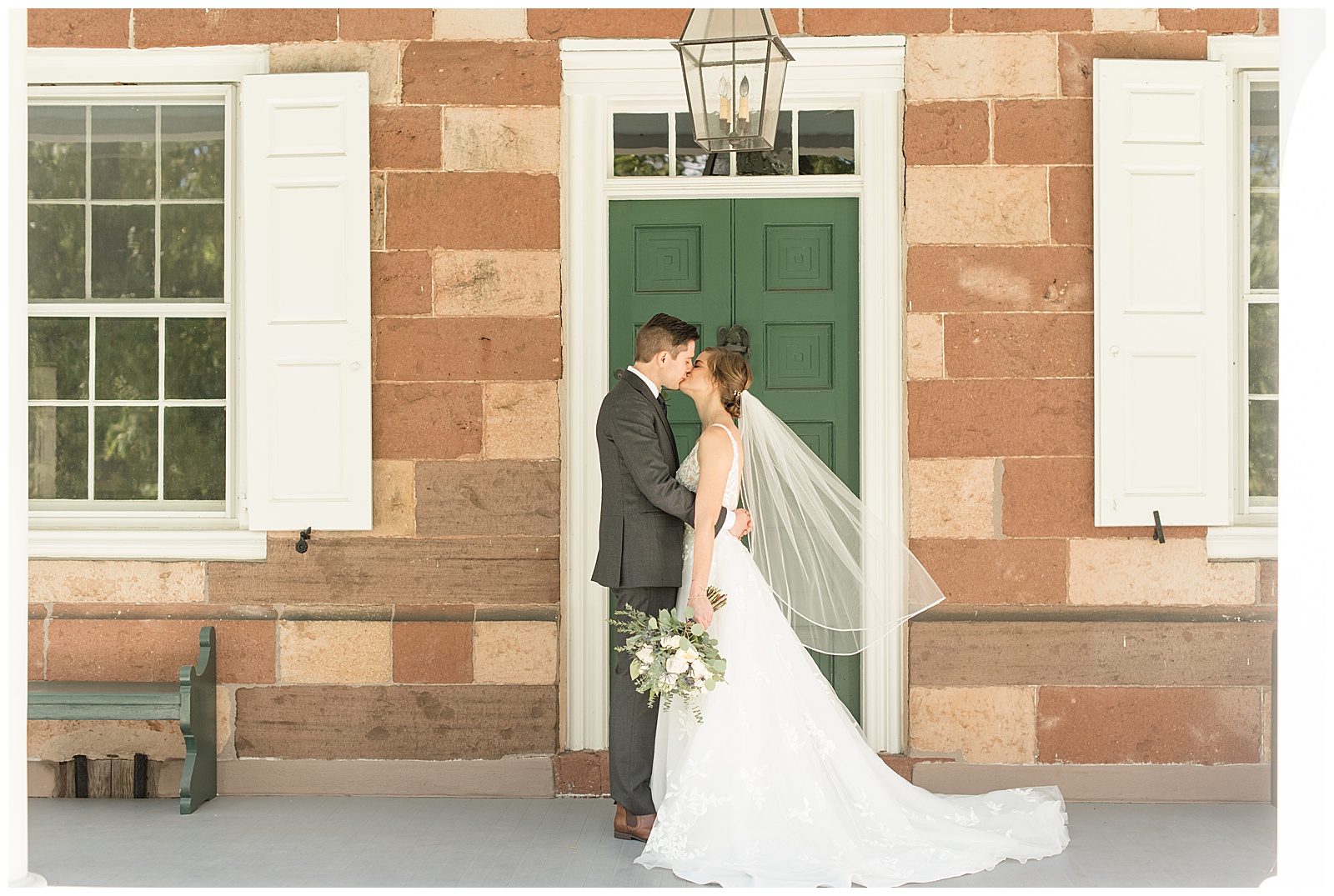 bride and groom kiss on front porch in front of emerald green door at elizabeth furnace