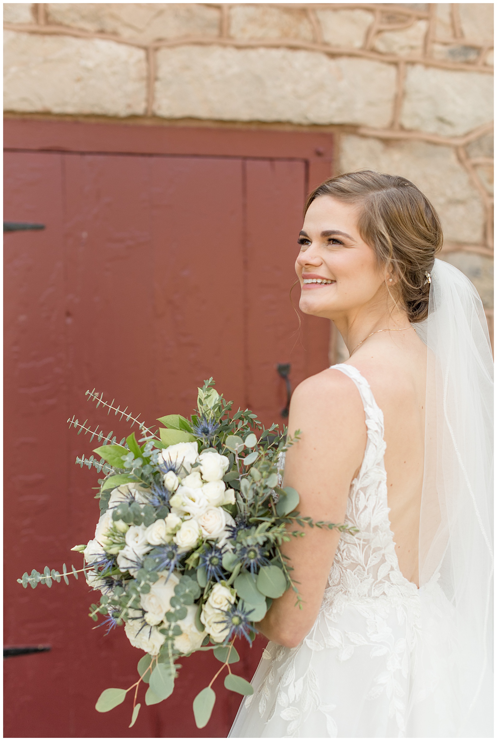 bride looking off to her left with her back to the camera as she smiles holding bouquet with white flowers and eucalyptus in lancaster county
