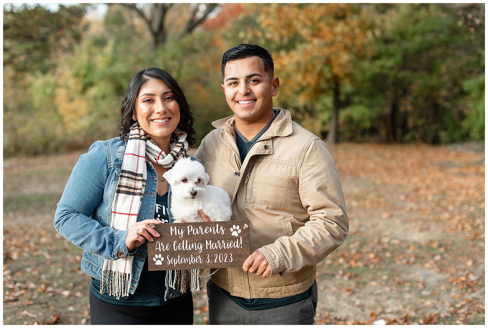 engaged couple holding their small white dog and small wooden save the date sign in lancaster county