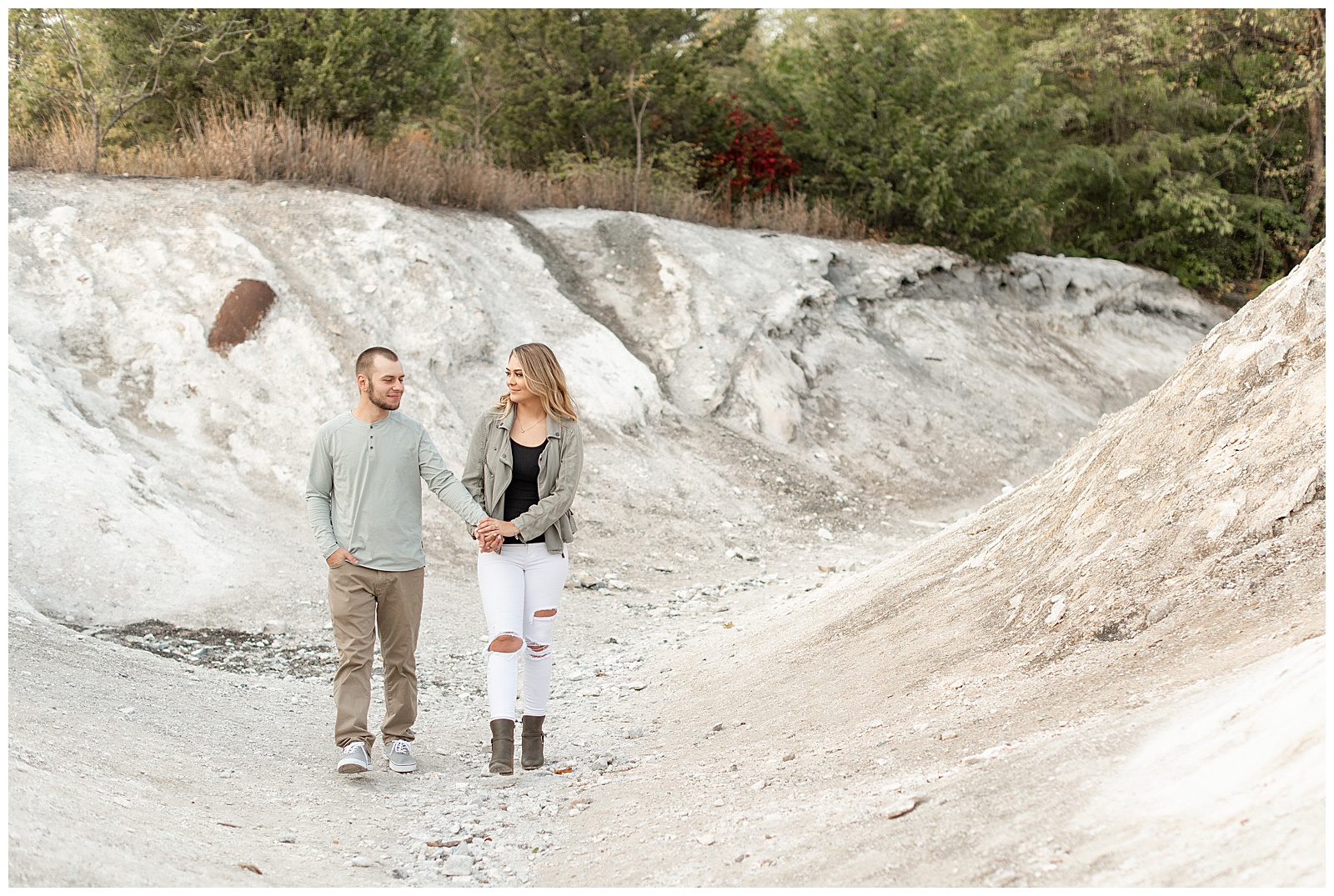 engaged couple holding hands and looking at each other as they walk toward camera on white cliffs of conoy