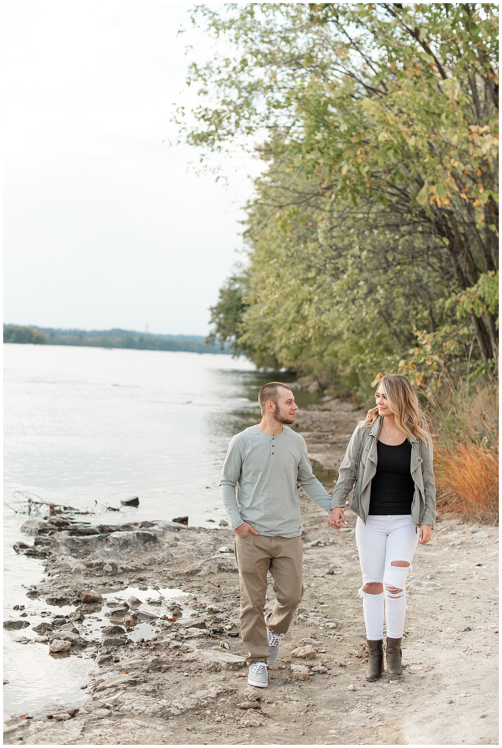 engaged couple holding hands and walking along shoreline of susquehanna river at the white cliffs of conoy