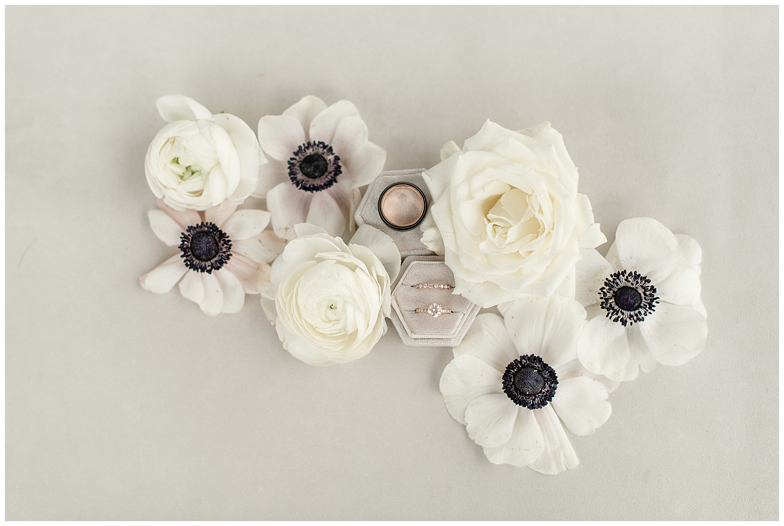 couples' wedding rings in boxes surrounded by white roses and white and black anemone flowers at historic ashland