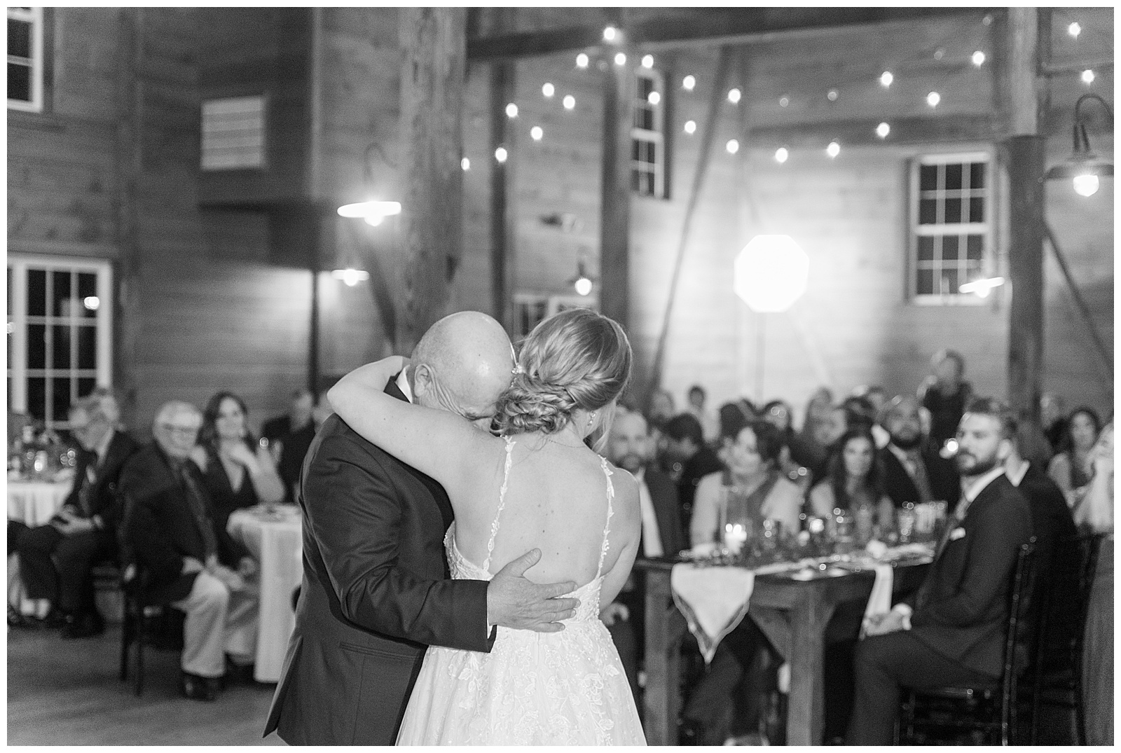 black and white photo of bride's father hugging her tightly during their father-daughter dance inside barn at historic ashland
