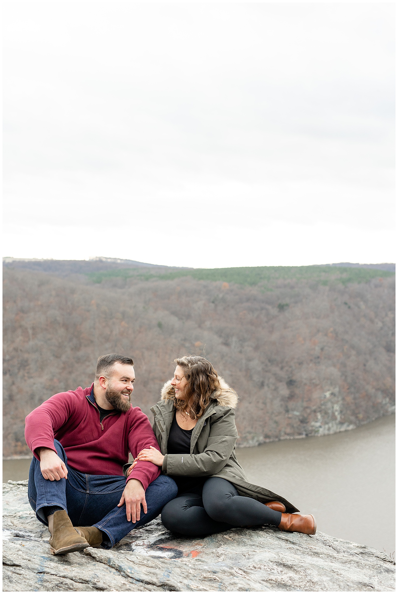 engaged couple sitting on rock looking at each other with susquehanna river behind and below them at pinnacle overlook