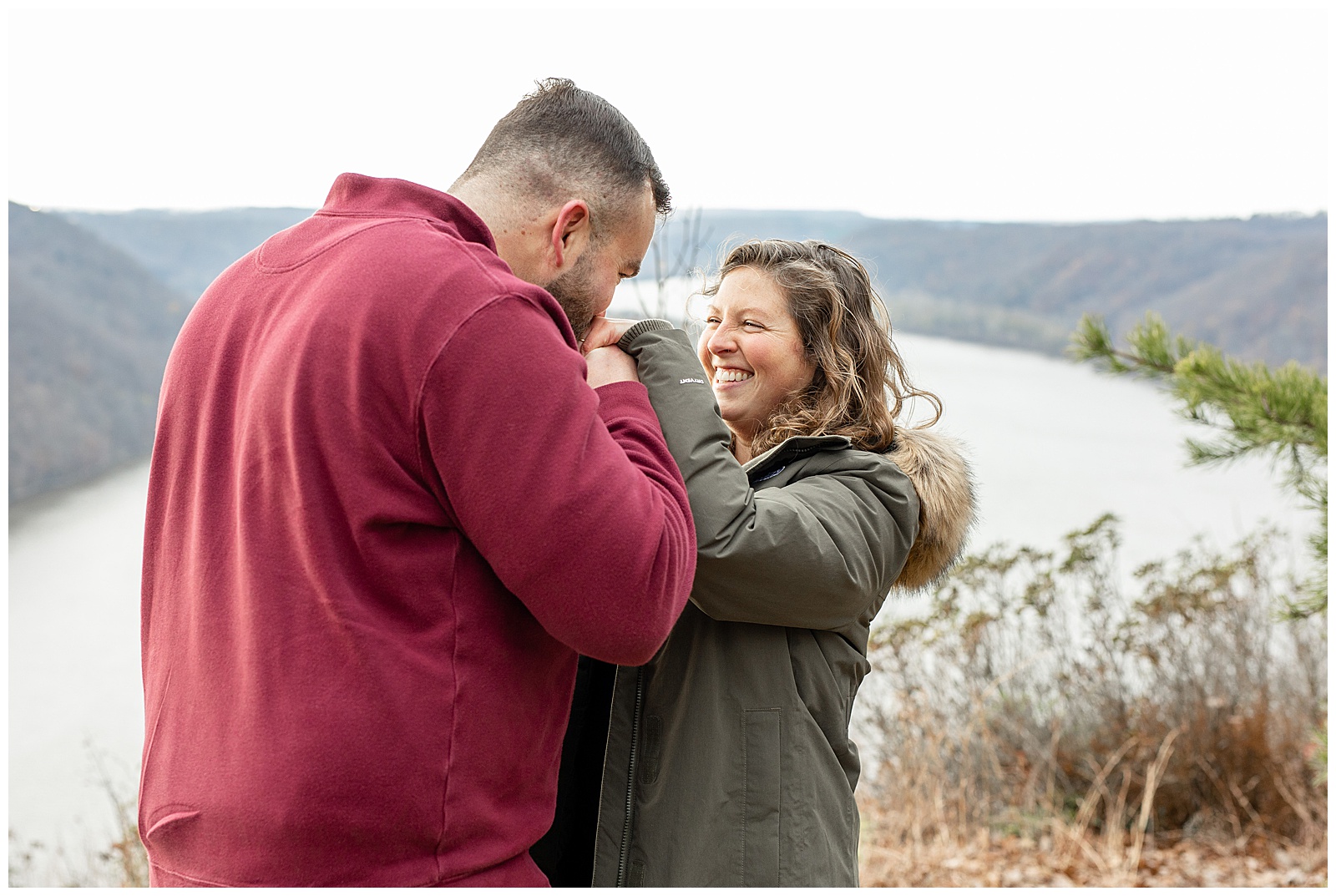 engaged couple laughing as guy kisses girl's hands at pinnacle point overlook