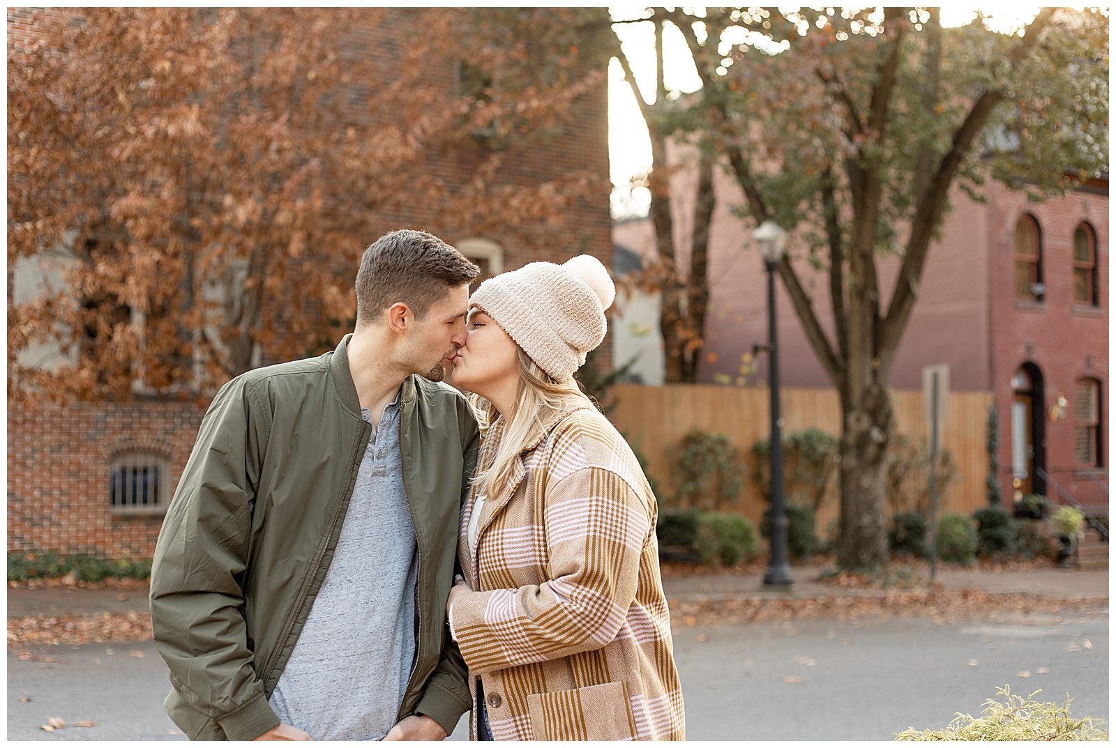 engaged couple kissing on chilly fall evening in downtown lancaster pennsylvania and standing close together
