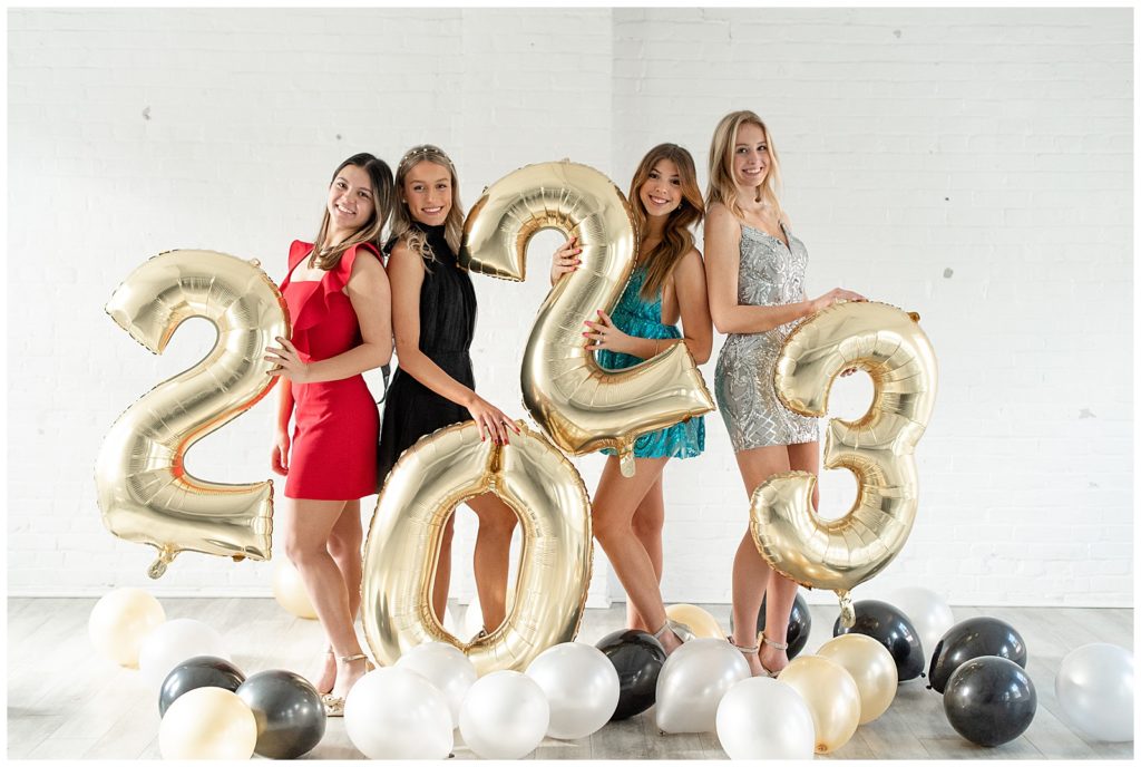 four senior spokesmodels each holding a balloon to spell out 2023 by white brick wall in The White Room Lancaster PA