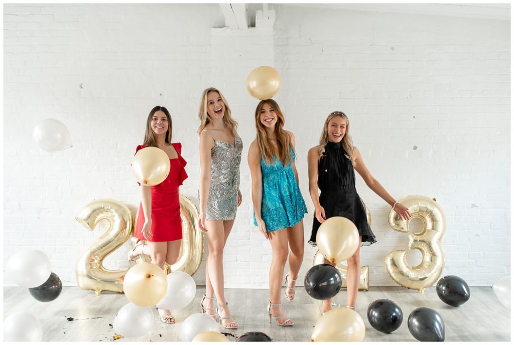 senior girls all celebrating at the white room with balloons and excitement in colorful party dress for new years