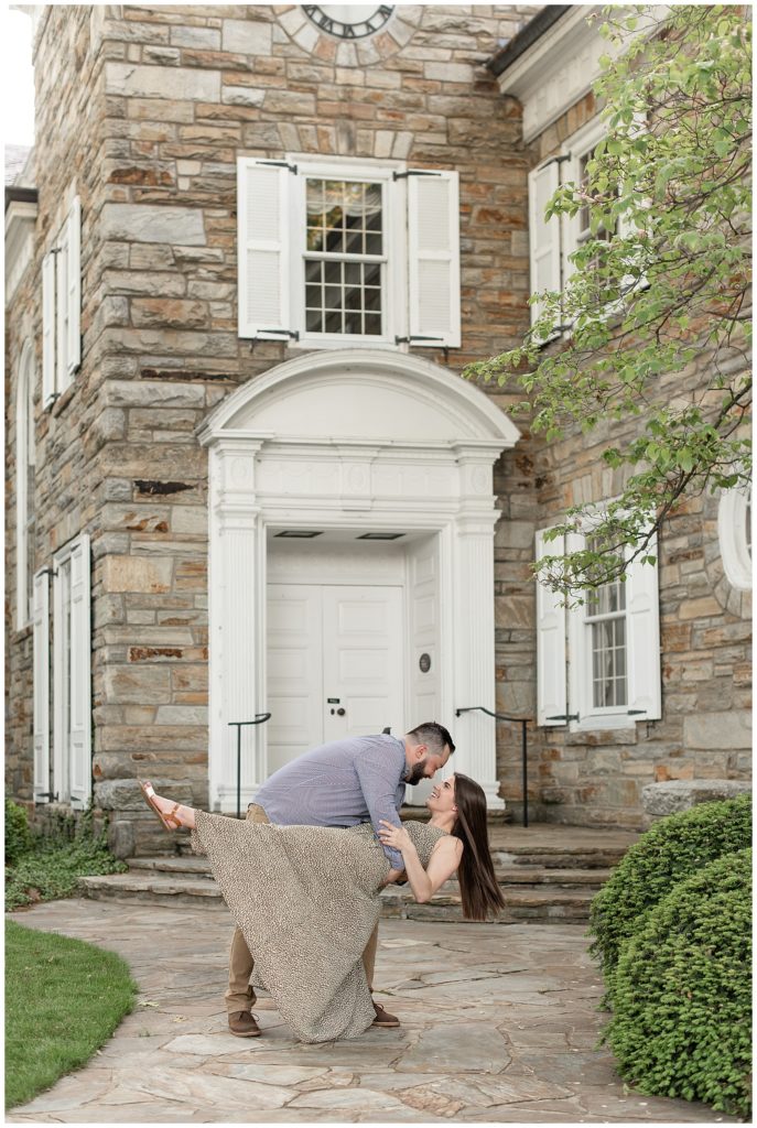guy dipping girl way back by stone steps of historic gray stone with white shutters building in downtown lititz pennsylvania