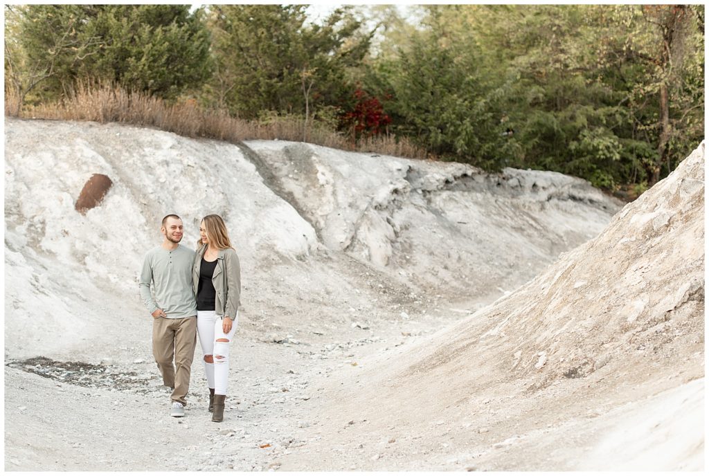 engaged couple hugging as they look at each other walking towards camera on white rock at the white cliffs of conoy