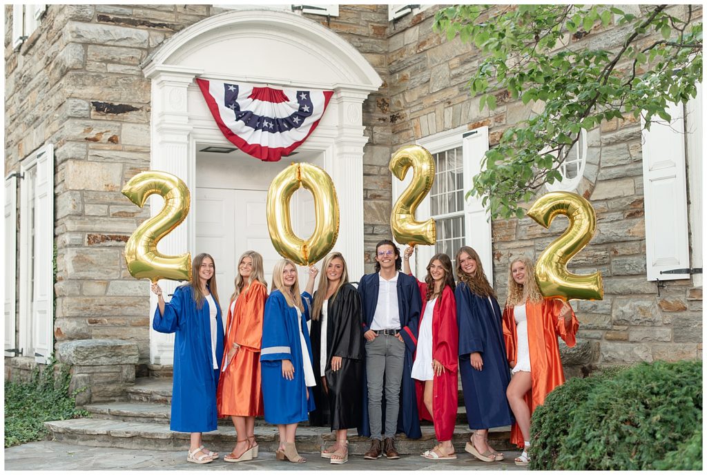 group of eight senior spokesmodels wearing each of their graduation gowns and holding 2022 balloons in downtown lititz