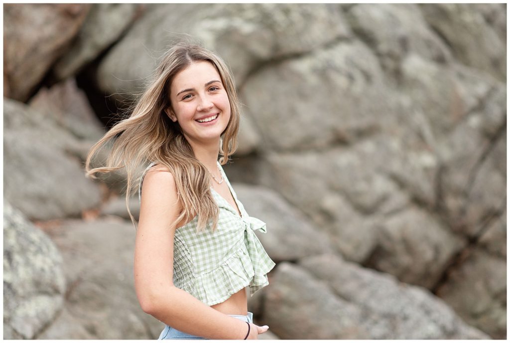 senior girl with right shoulder towards camera and smiling with large rock in background at samuel lewis state park